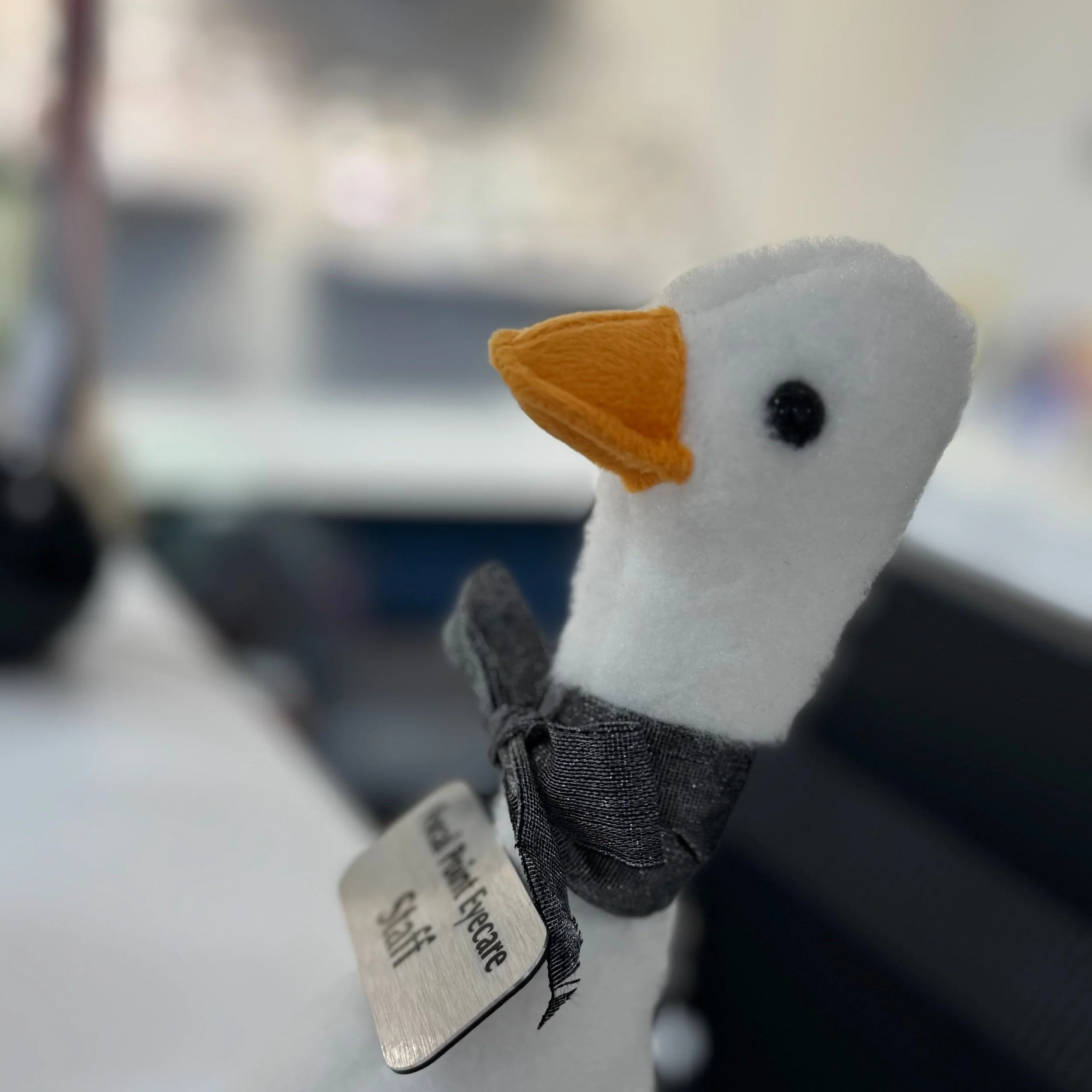 small goose stuffy with bow tie and Staff name tag looking off into the distance