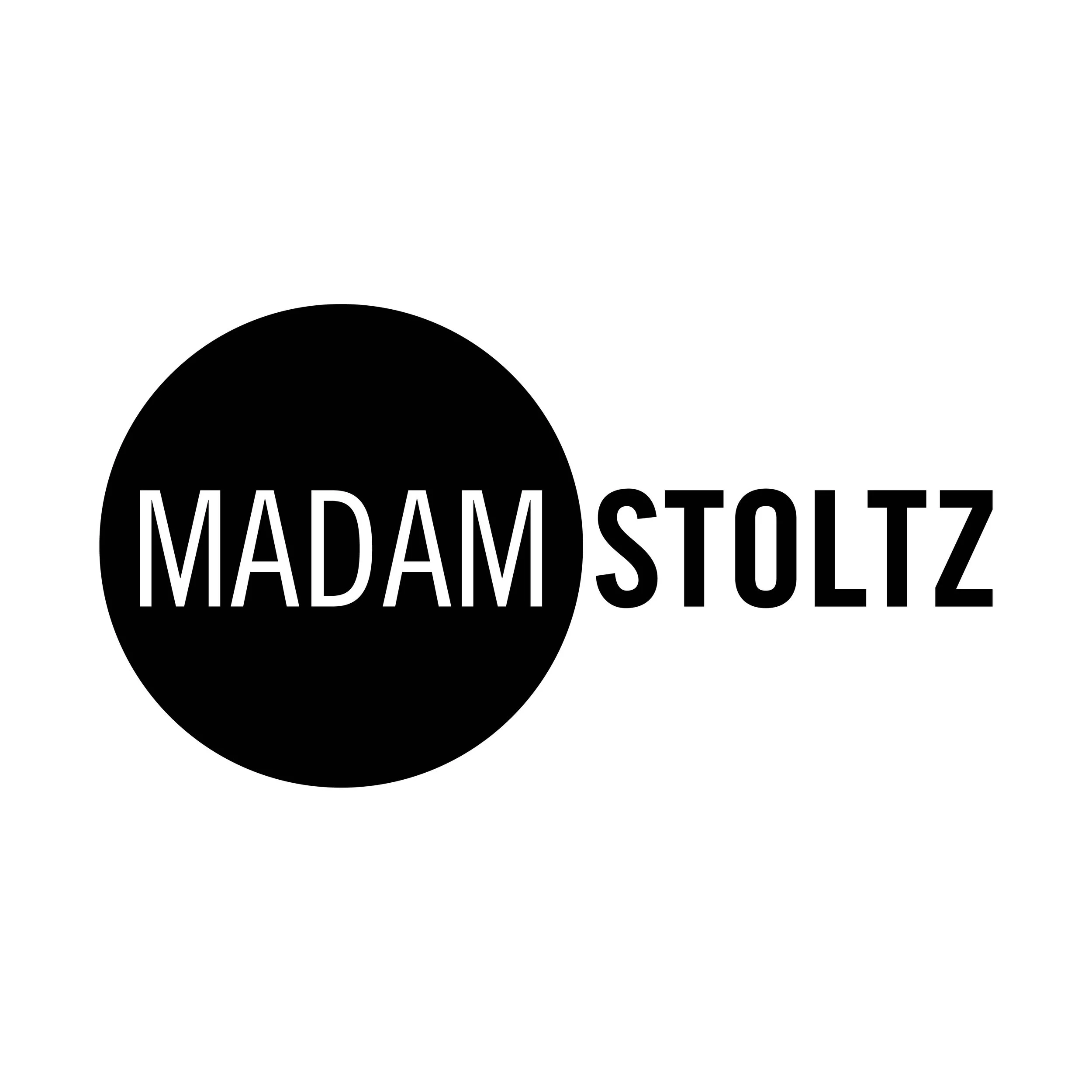 Svart cirkel med vitt text som säger 'MADAMOSTOITZ' på en vit bakgrund.