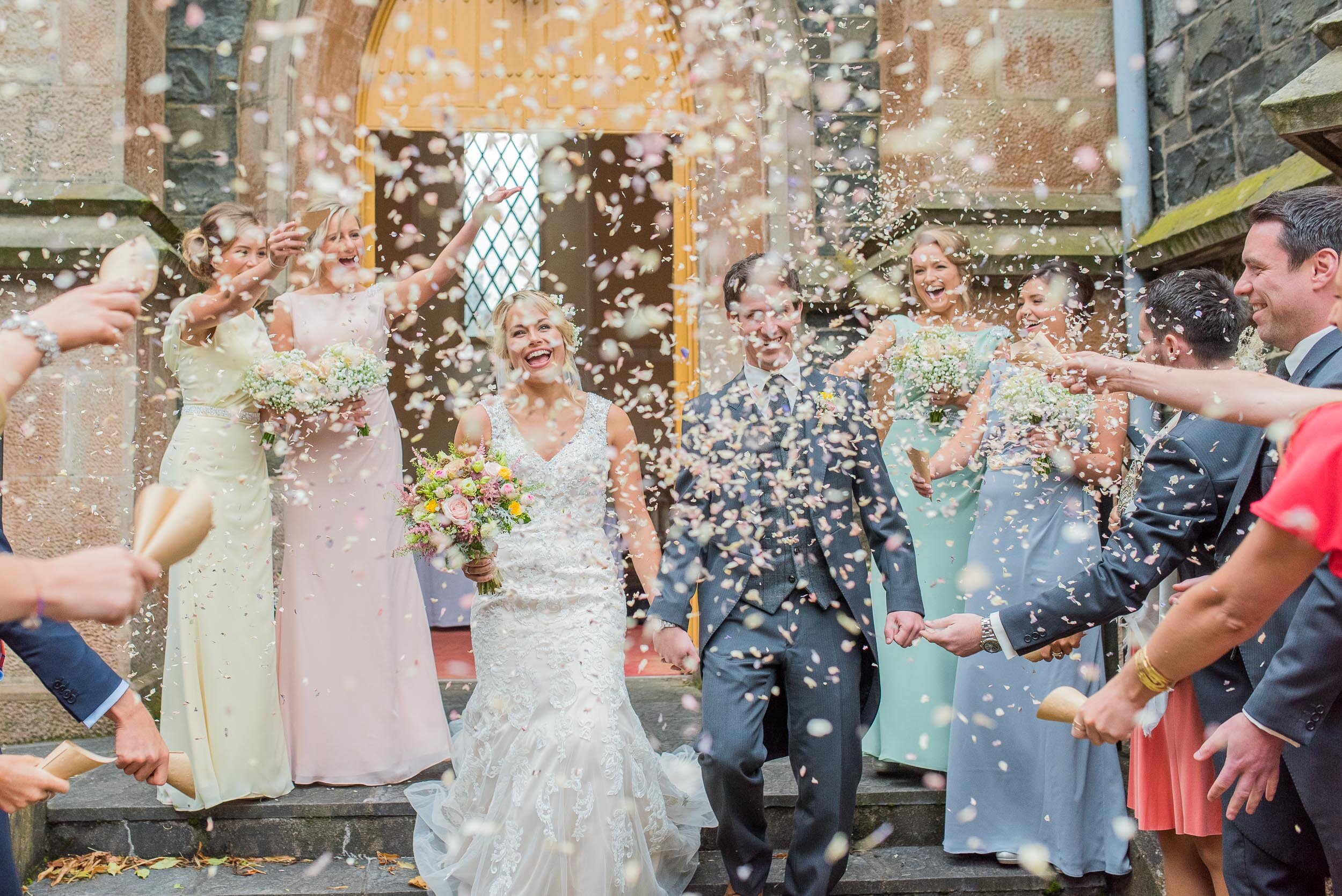 Bride and groome outside church with confetti