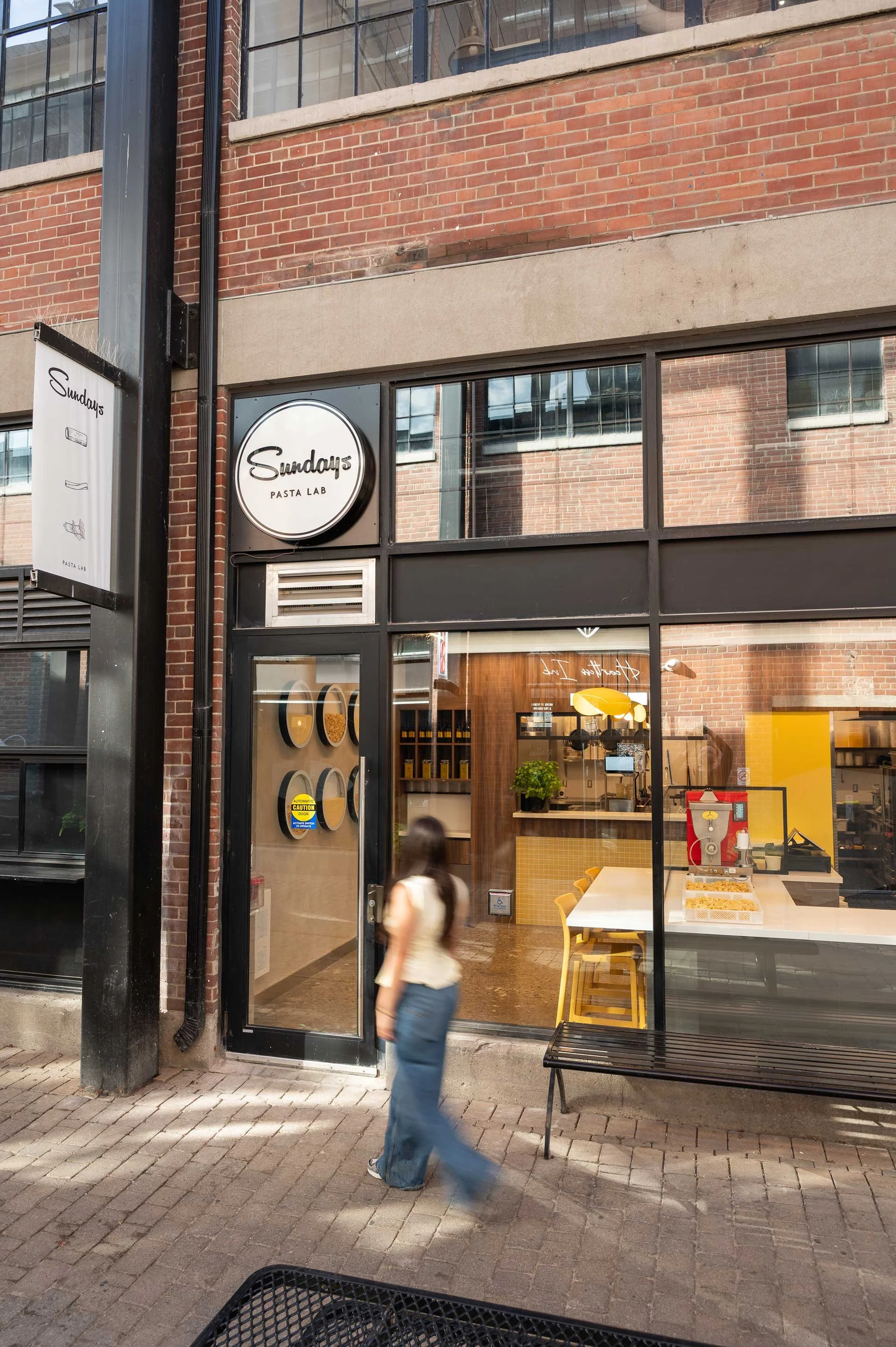 Sunday's Pasta Exterior, tall windows with black mullions, women walking into