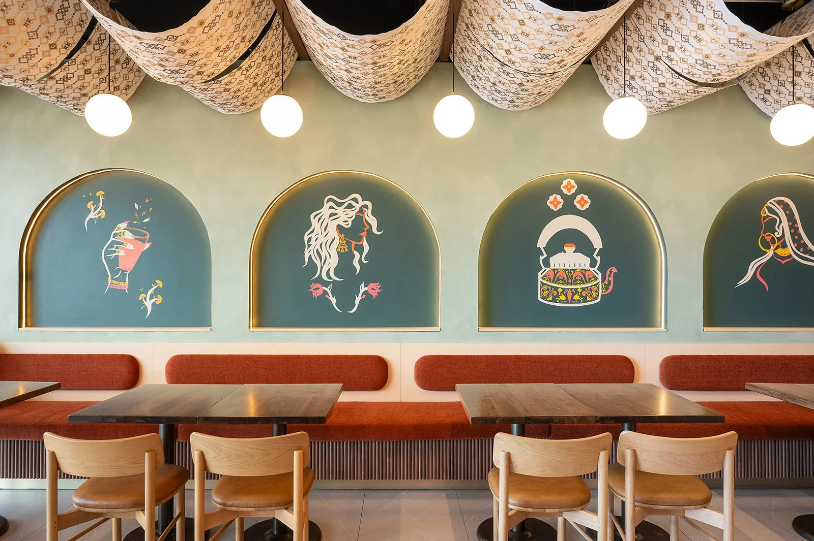 Hospitality interior design with mural-painted arched wall niches and rust-orange banquette seating in a Toronto café by Sansa InteriorsCoffee shop design in Toronto