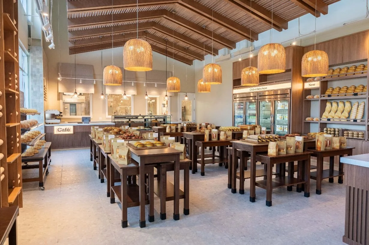wide view of bakery and nested wood display tables with a custom wood canopy and pendant lighting above