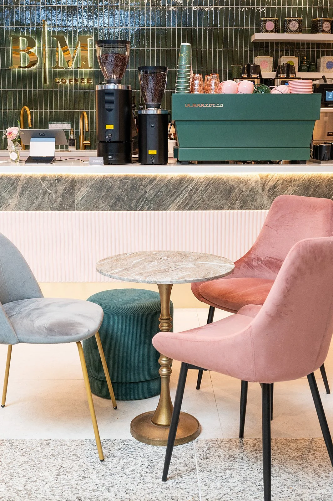 seating and counter of the Blossom Moments café counter design at Scotia Plaza, Toronto, with brass pendant lighting and green tile backsplash