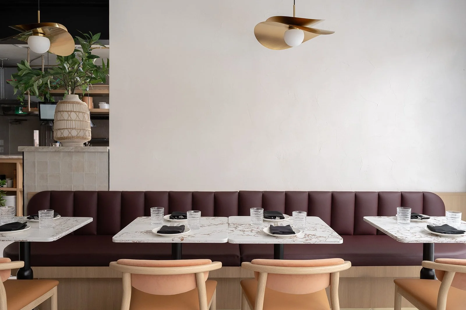 Italian restaurant banquette with white plaster wall and brass pendant above