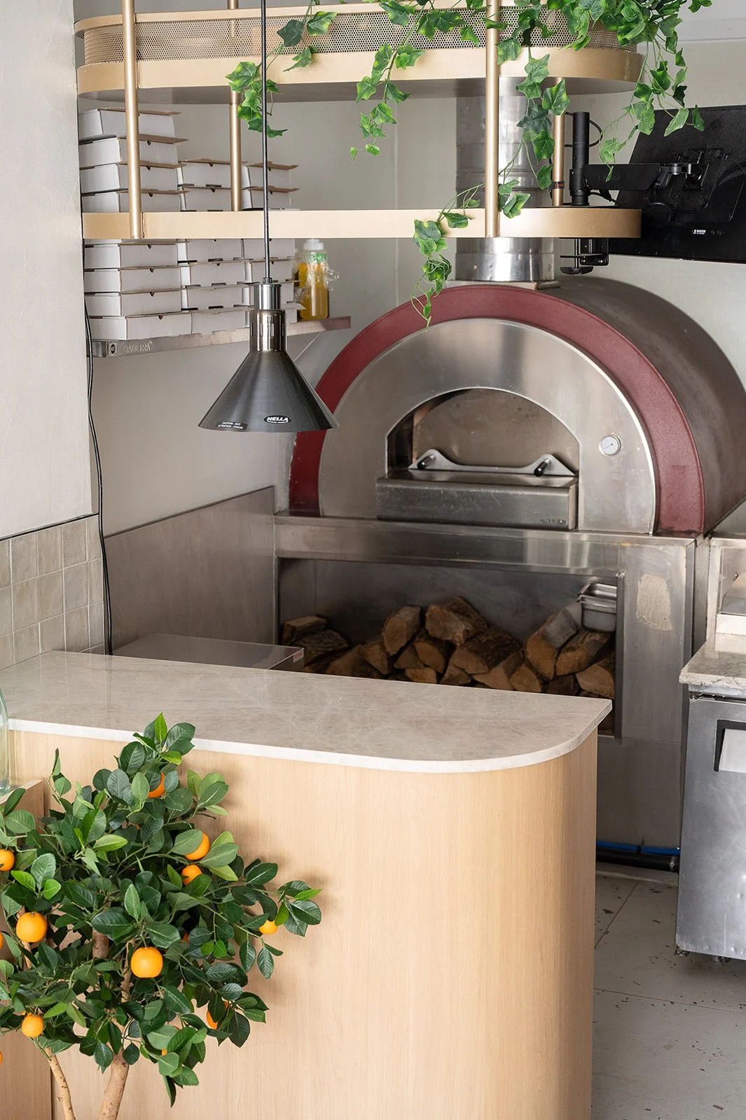 Italian restaurant pizza oven behind a white oak and quartz counter