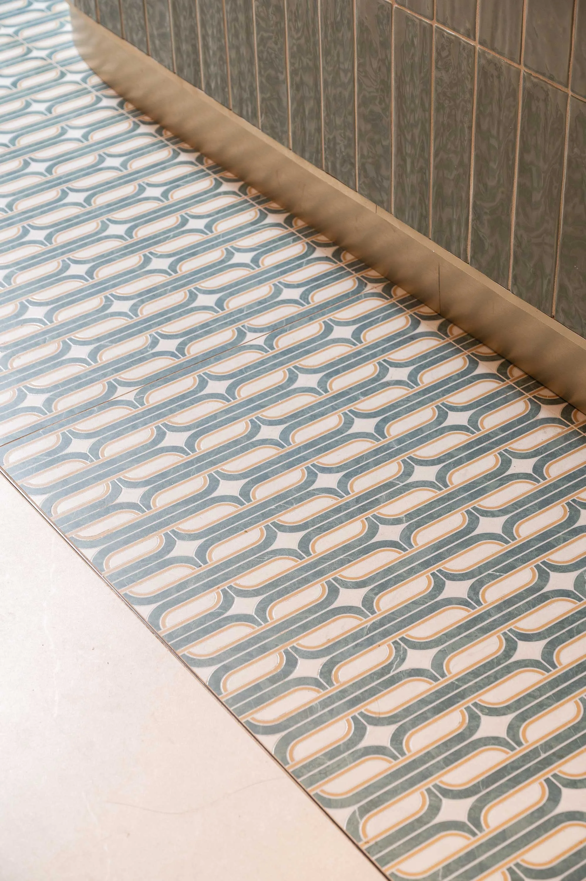 Geometric green tile floor inlay around counter brass base 