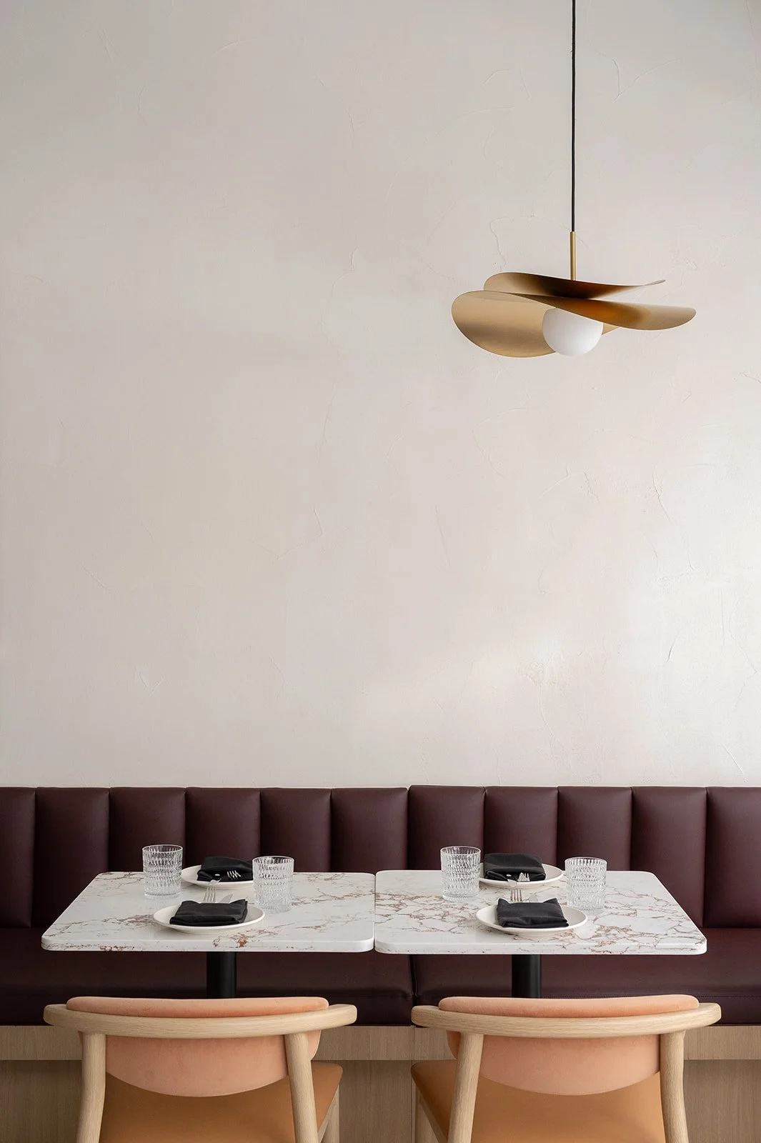 Italian restaurant banquette with white plaster wall and brass pendant above