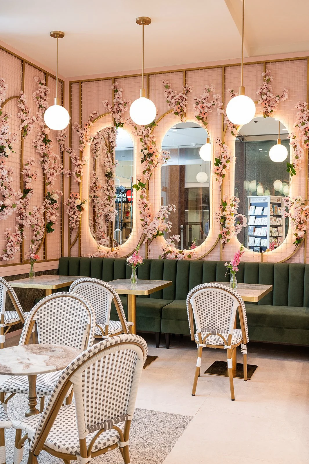 Arched cherry blossom mirrors above green booth seating separating the cafe zone from the floral retail area at Blossom Moments Scotia Plaza