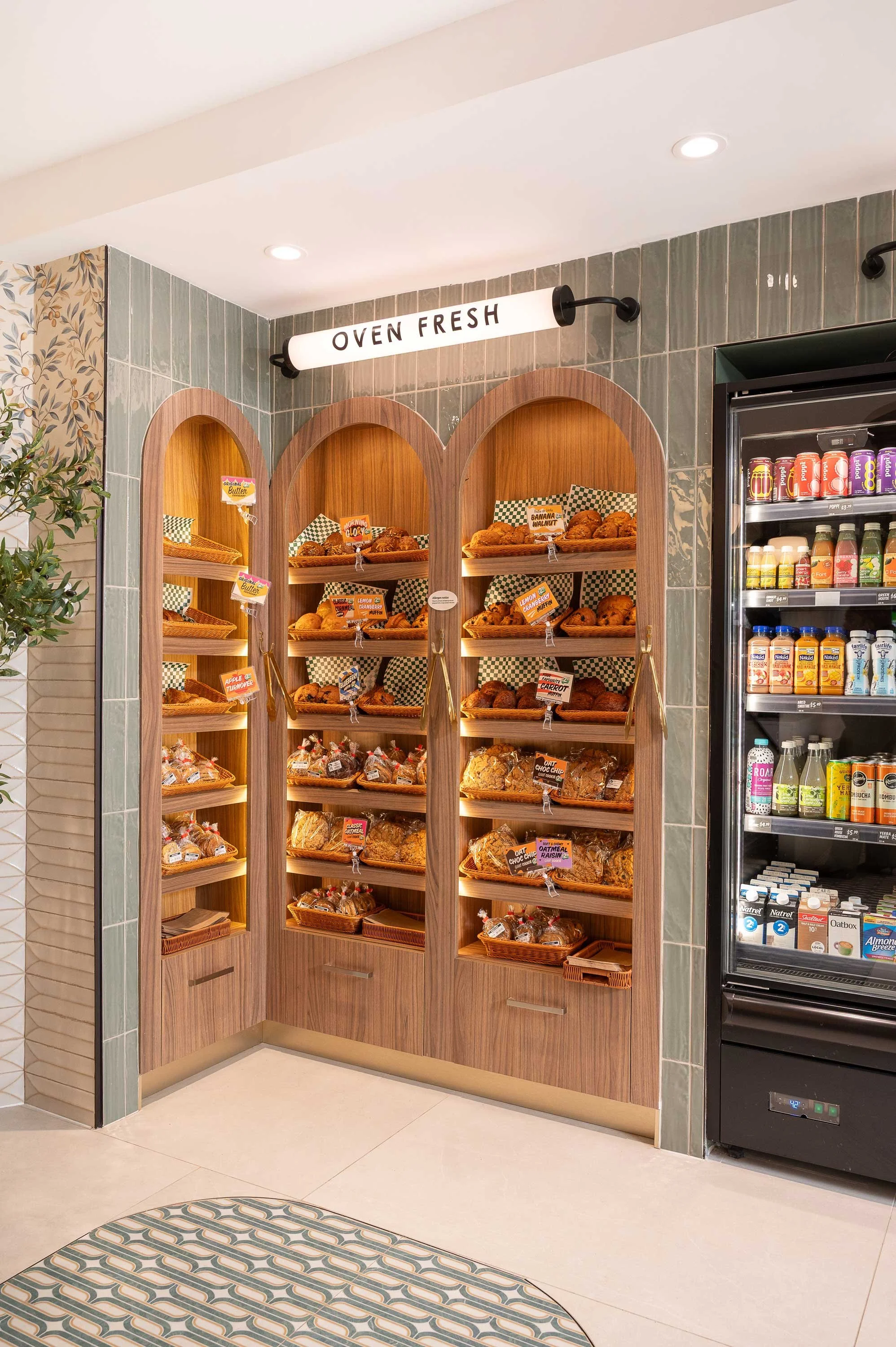 Recessed arched bakery display made from a light walnut wood with illuminated tube signage above