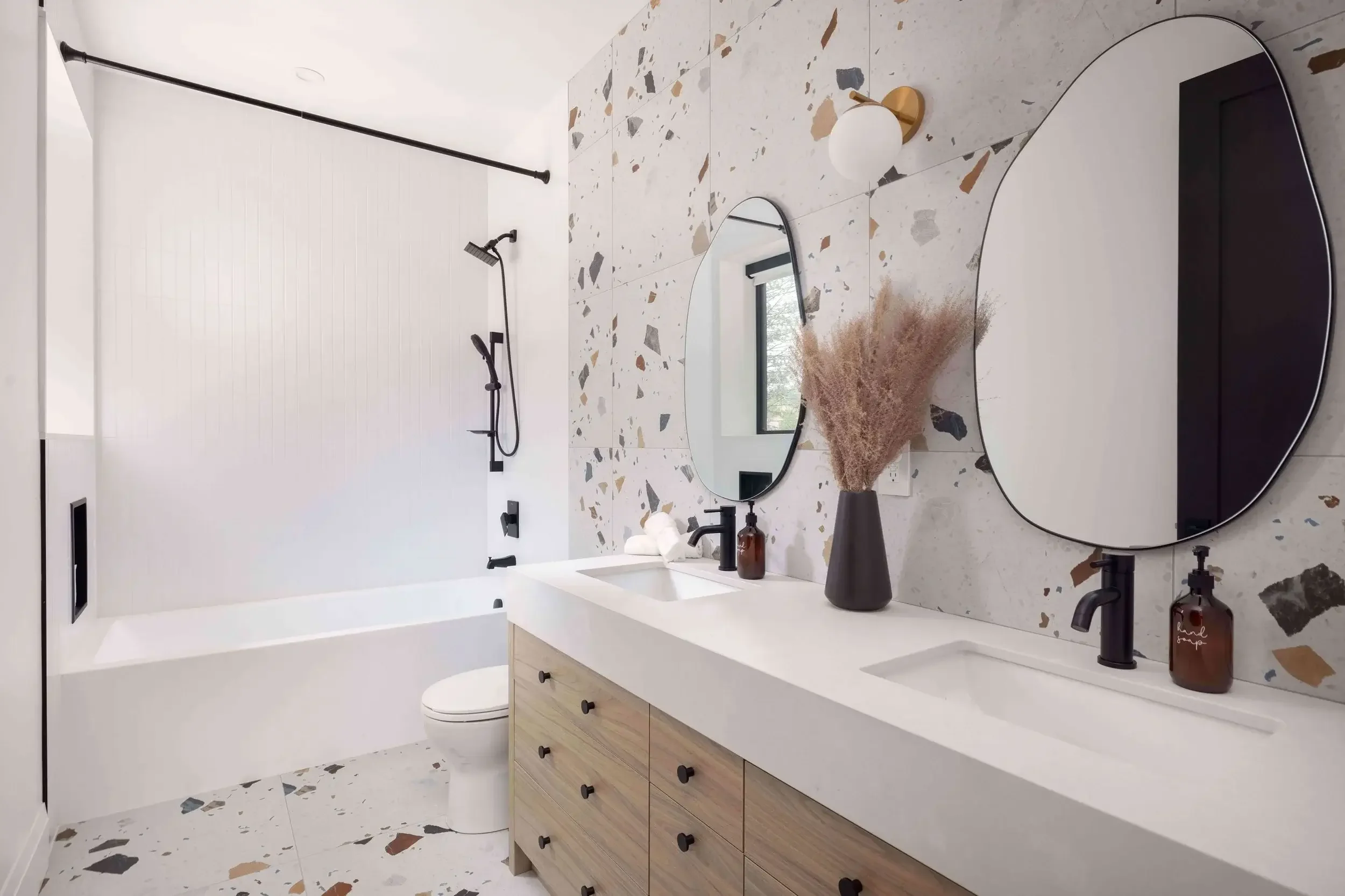 Modern bathroom interior design with terrazzo tiles, double vanity, and minimalist black fixtures