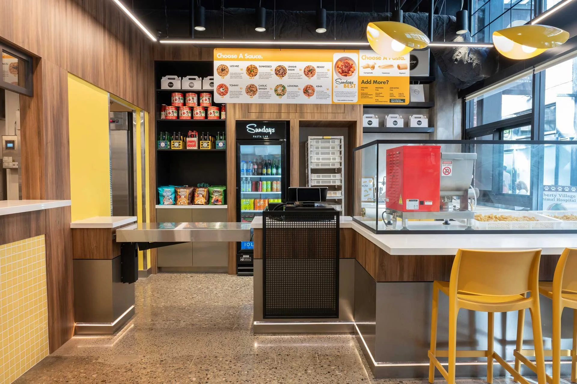 Pasta restaurant interior, customer check out counter with wood detailing and stainless steel.
