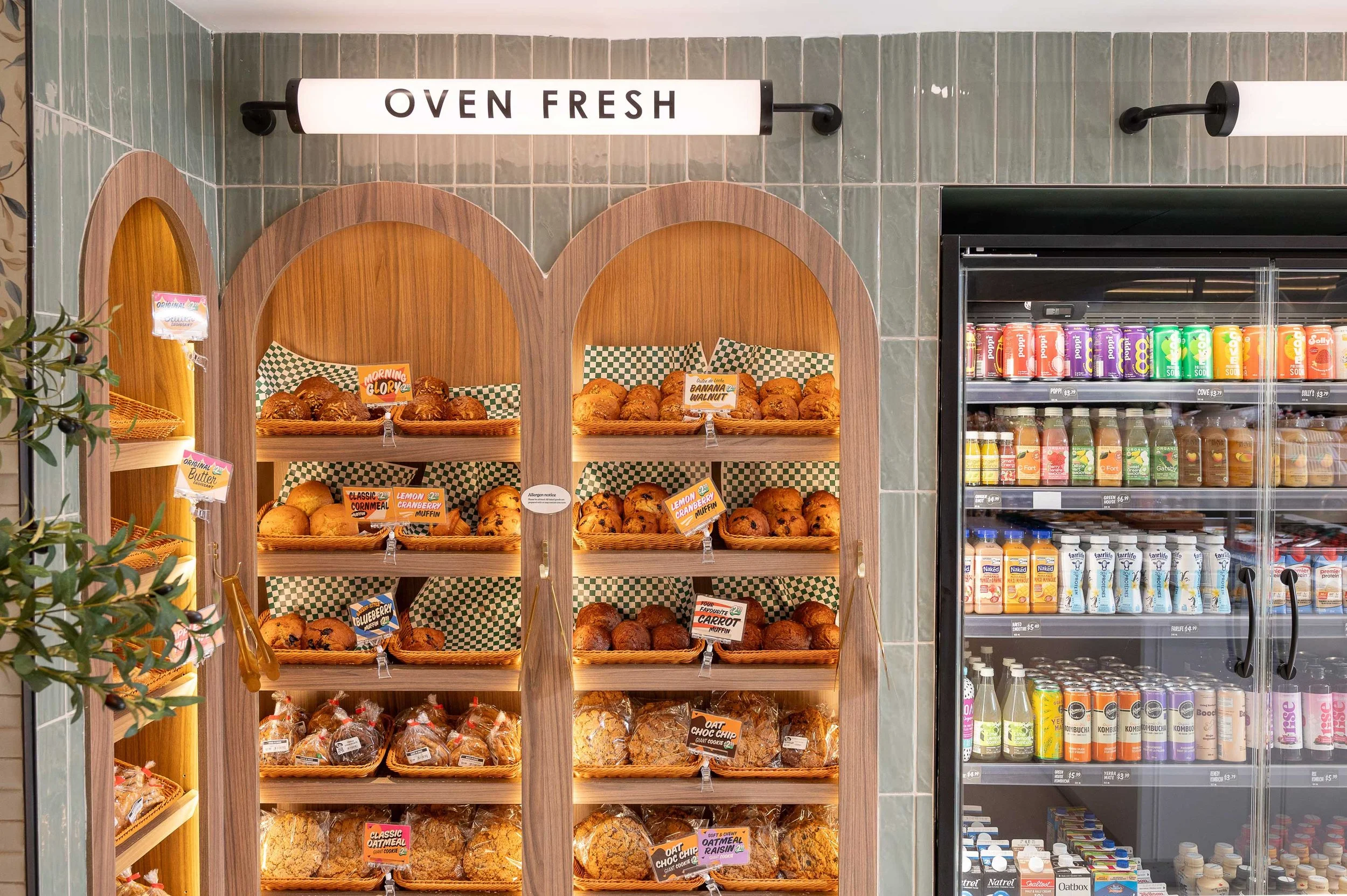 Custom wood display shelving with arched niches for pastries and grab-and-go drinks in a Toronto café designed by Sansa Interiors
