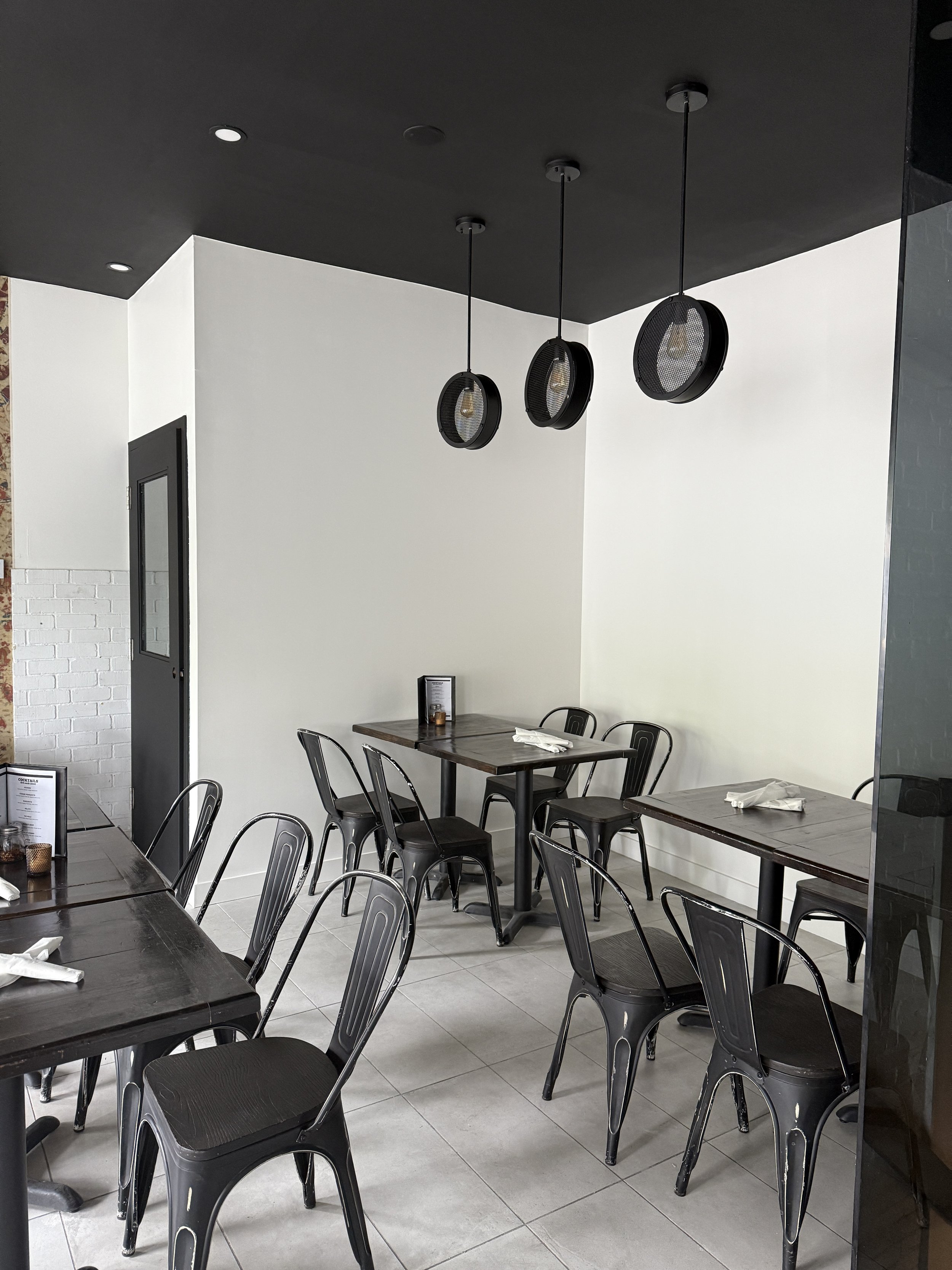 Restaurant before renovation, all white walls, black ceiling, and black lighting and furniture