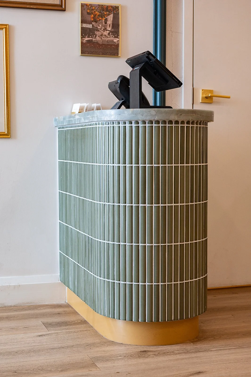 Tabule Oakville reception area with sage green fluted tile host stand and brass hardware designed by Sansa Interiors