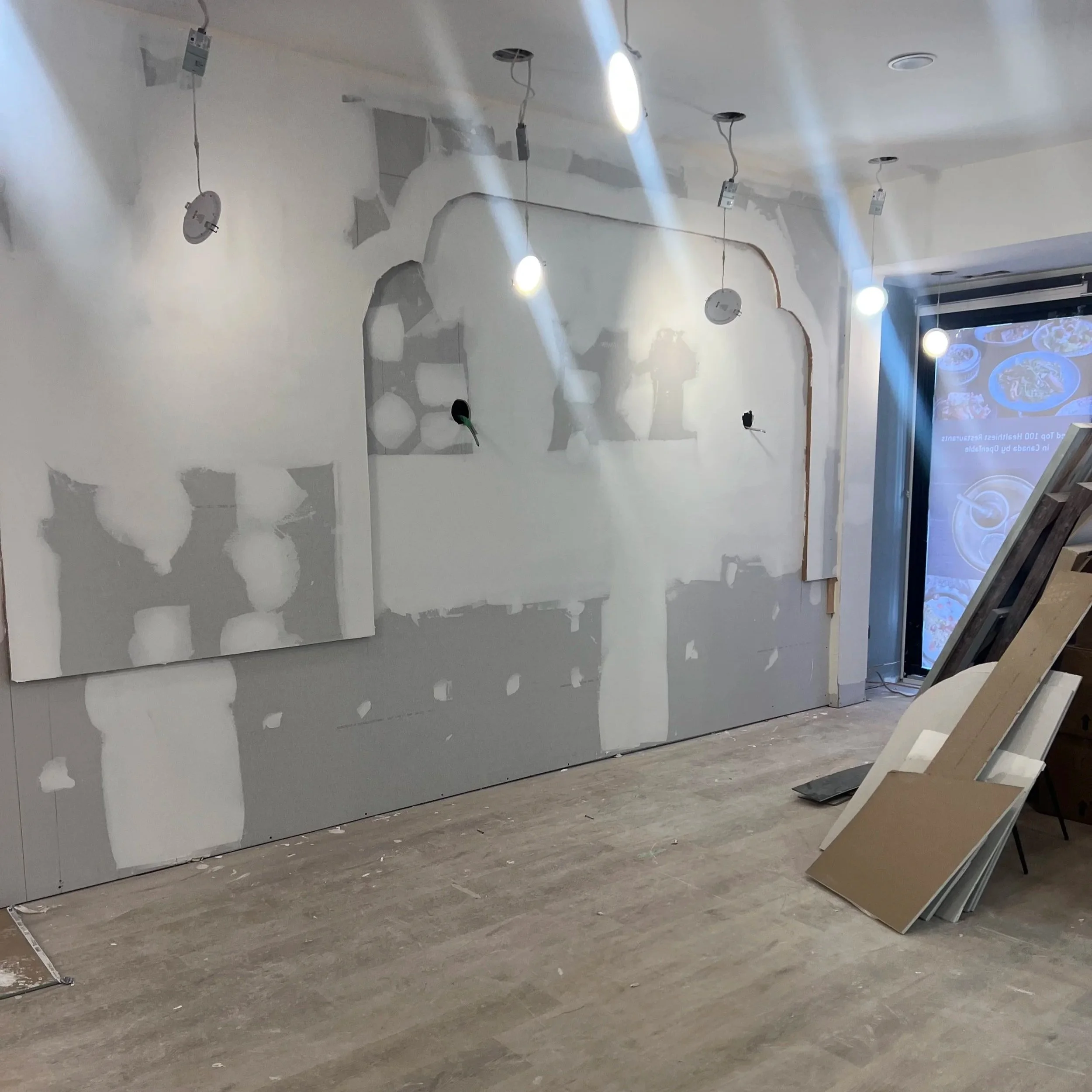 Tabule Oakville restaurant interior construction showing arched wall forms and raw drywall before design installation