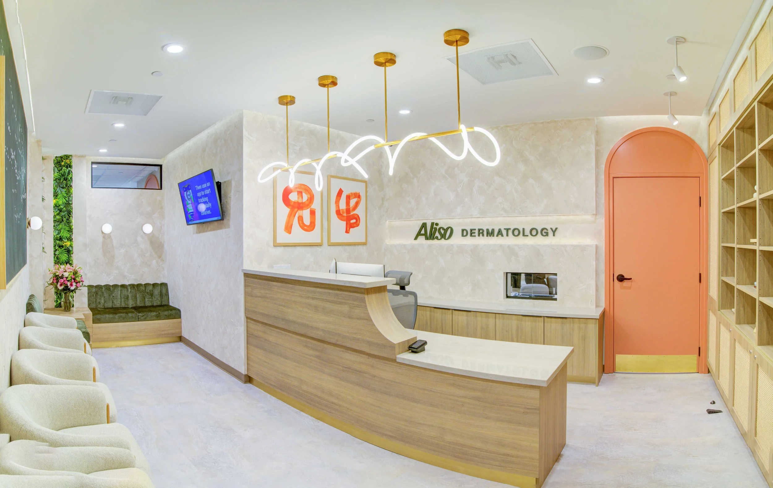 Wide view of the modern Aliso Dermatology clinic reception and waiting area featuring a warm wood desk, custom loop LED lighting, and comfortable seating.