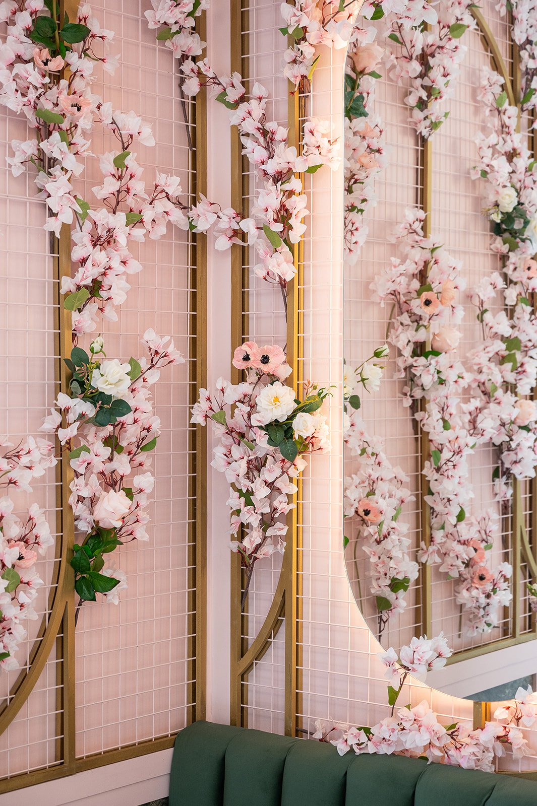 Double arched mirrors framed with cherry blossom branches above the green booth seating at Blossom Moments Scotia Plaza