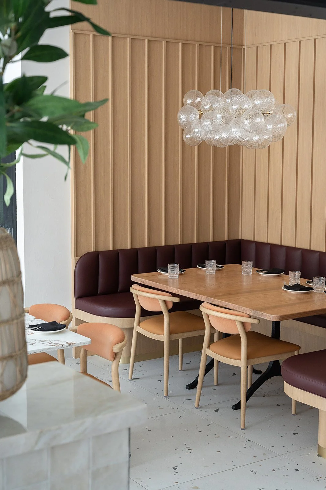 Italian restaurant U-shaped booth with glass bubble pendant, slatted white oak walls and burgundy leather seating