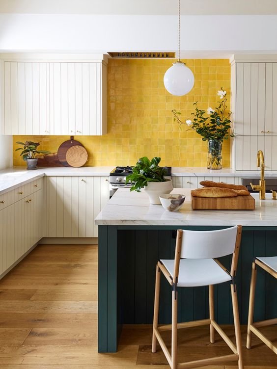A bright kitchen with white cabinets and a vibrant yellow tile backsplash