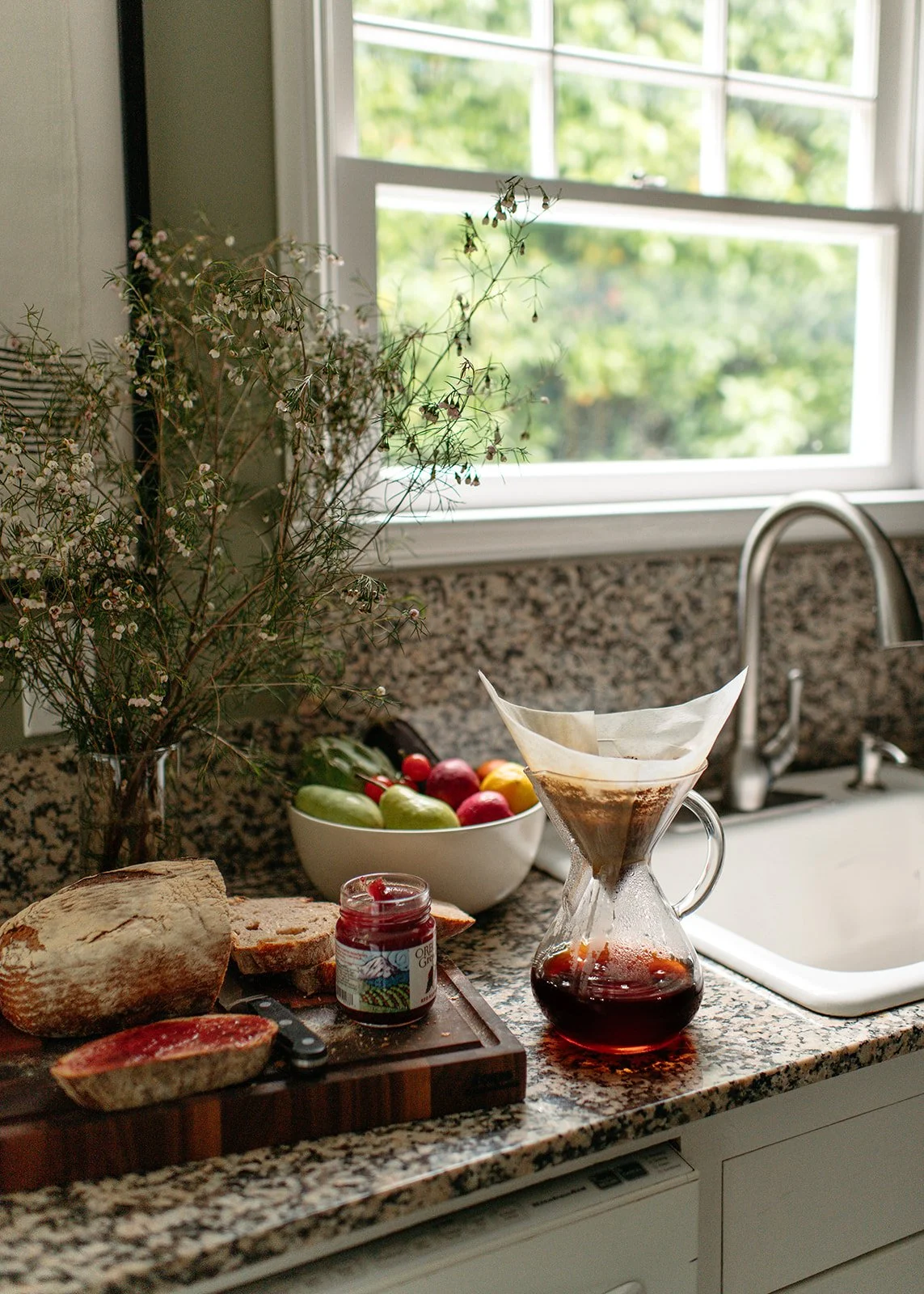 Kitchen countertop with homemade bread, jam, juice, fruit, and more