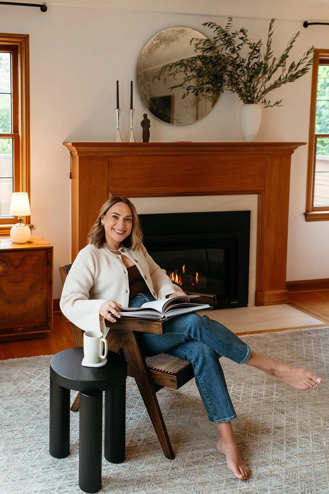 Portland OR's award-winning realtor, Alison Derse, reading a book and drinking coffee in a warm, perfectly staged living room
