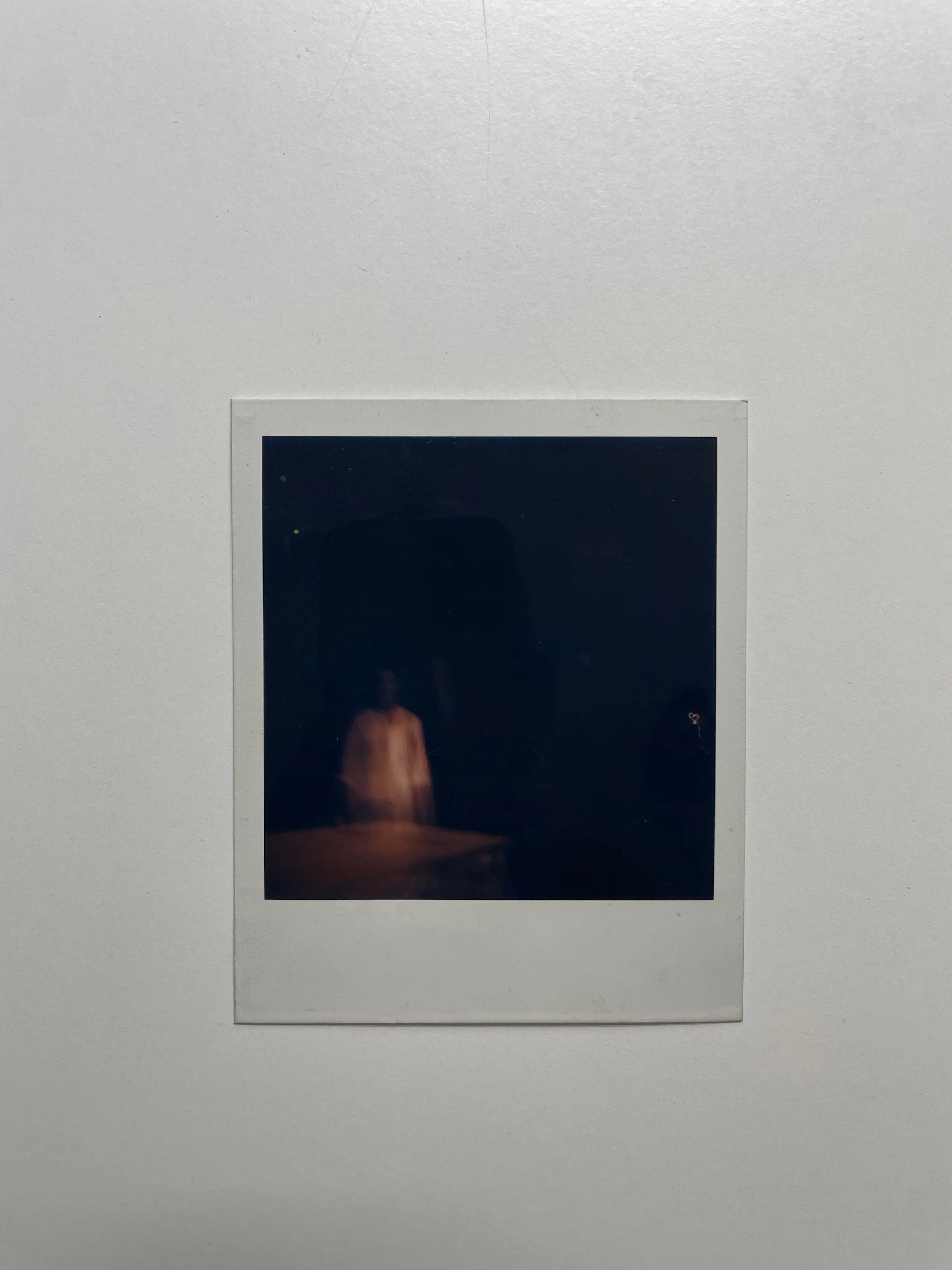 A polaroid photo of a person dressed in white against a dark background