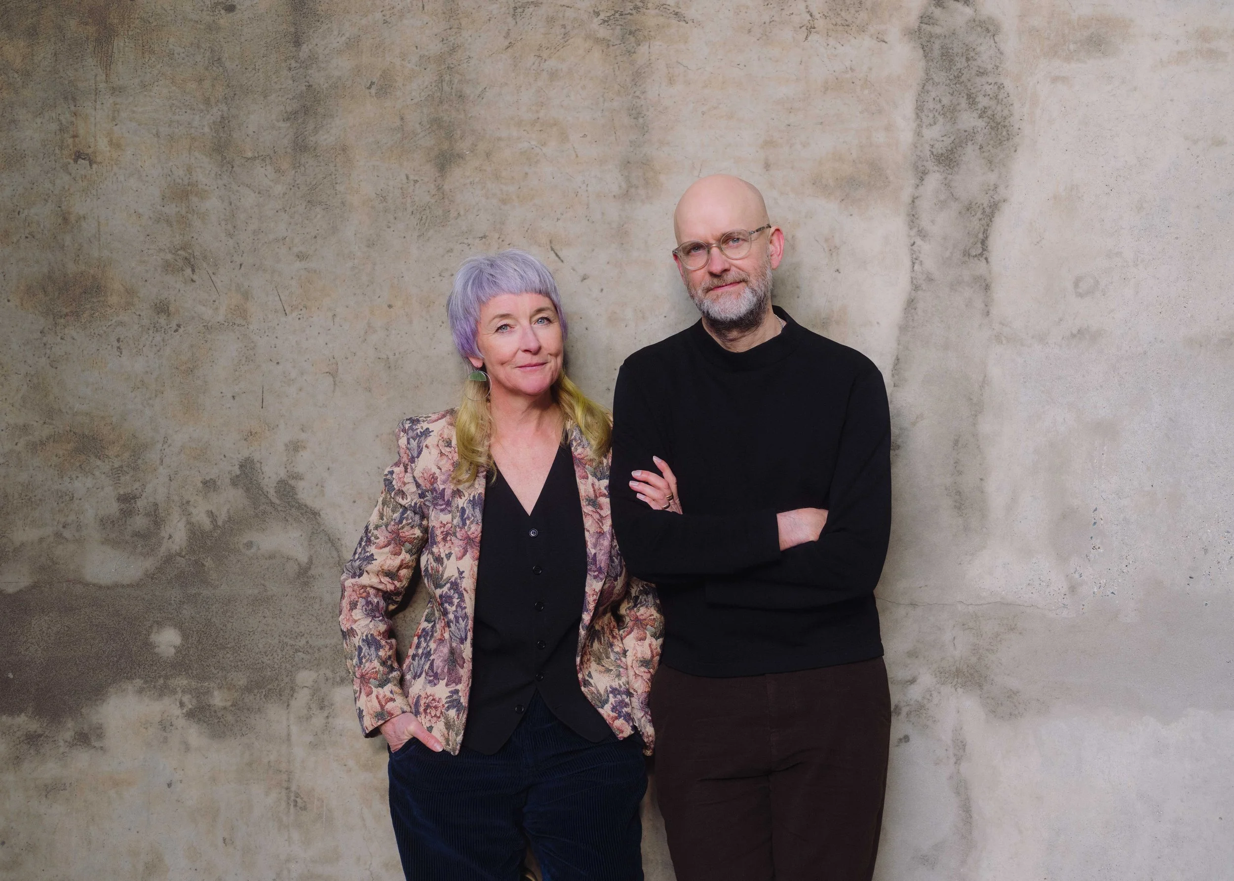 A woman and a man stand together looking at the viewer