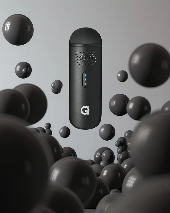 A portable black Google Stadia streaming device surrounded by floating black balls against a plain gray background.