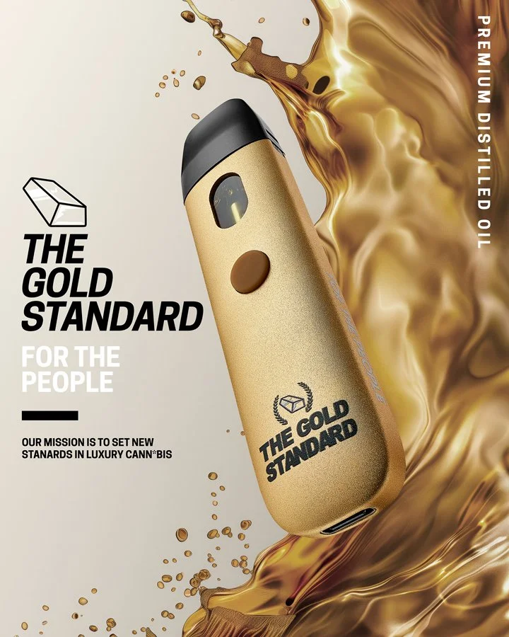 A portable vaporizer in gold color with black top, branding for "The Gold Standard" with a logo of a wrapped gift box. The vaporizer is shown with a splash of gold liquid or oil around it, emphasizing premium quality. Text on the left mentions "Premi