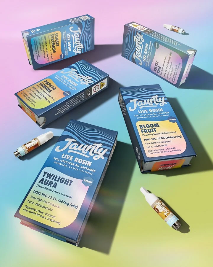 Boxes of Tauntz live rosin cannabis product with individual vape cartridges and a small vape device on pastel purple and green background.