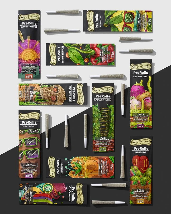  assorted pre-rolled cones of cannabis, each in colorful packaging with themed illustrations and labels, laid out on a surface.