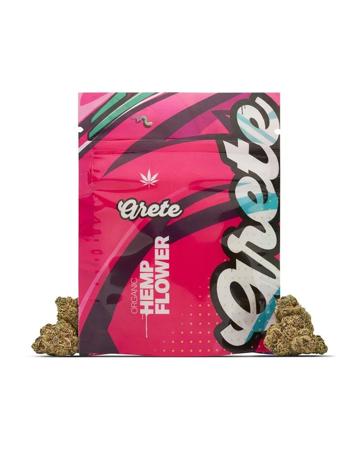 A colorful package of Crete Organic Hemp Flower with pink and black design, surrounded by hemp buds.