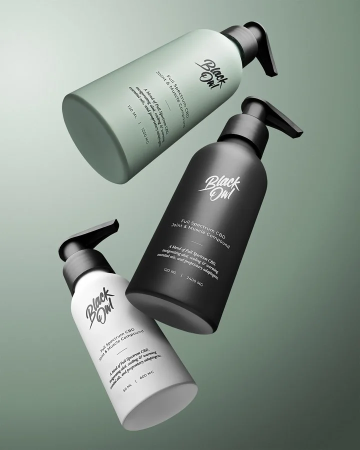 Three spray bottles of Black Onyx CBD product arranged diagonally on a green gradient background, with varying sizes and colors including white, black, and greenish-gray.