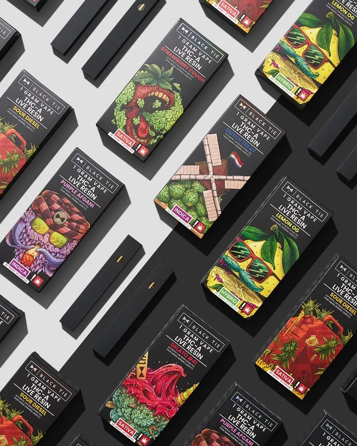 Assortment of vape product boxes with colorful, artistic cannabis-themed illustrations arranged on a gray surface.