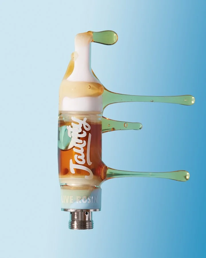 A glass bottle with the Jack Daniel's logo, containing liquid, with splashes of the liquid extending outward like ejected droplets against a light blue background.