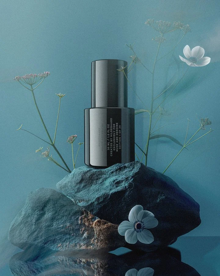 A black bottle with white text on it, placed on a large rock surrounded by delicate white and pink flowers, with a soft blue background.
