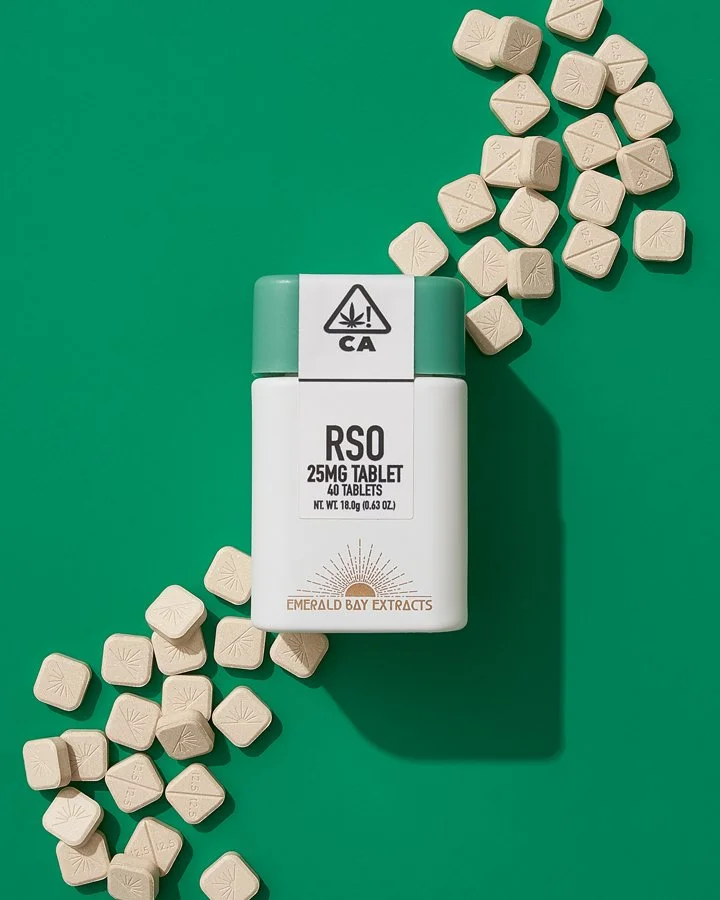 A white and green container labeled RSO 25MG tablets with 40 tablets, surrounded by scattered beige tablets on a green background.