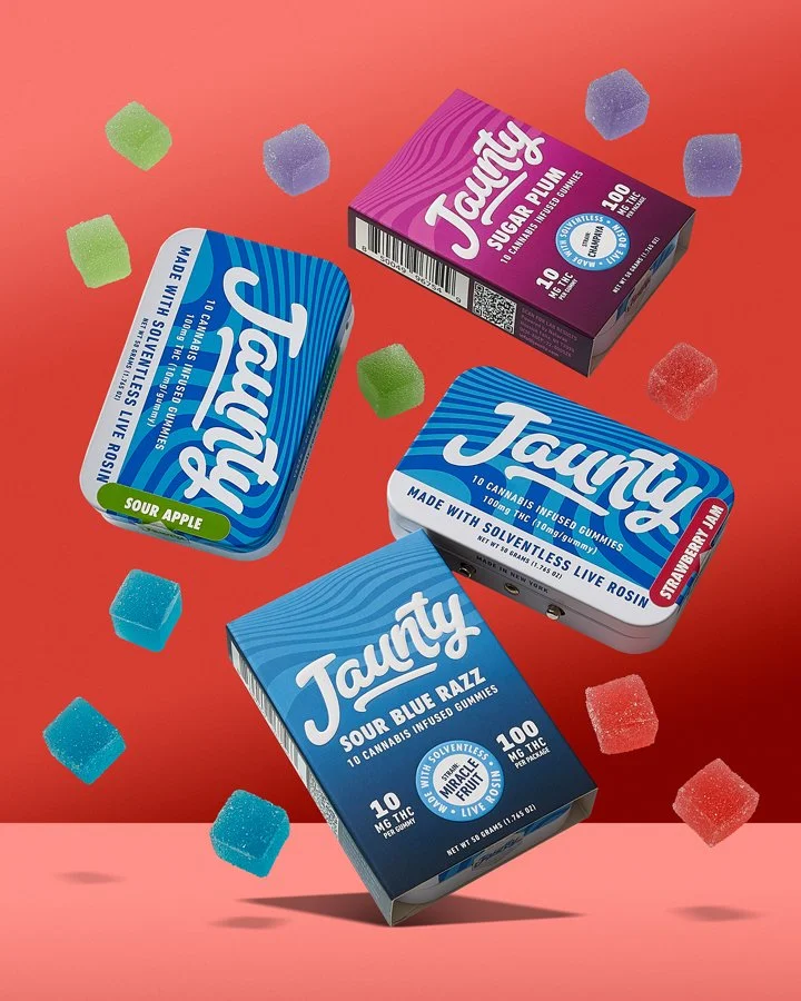Assorted gummy candies and cannabis-infused gummy boxes on a pink background.