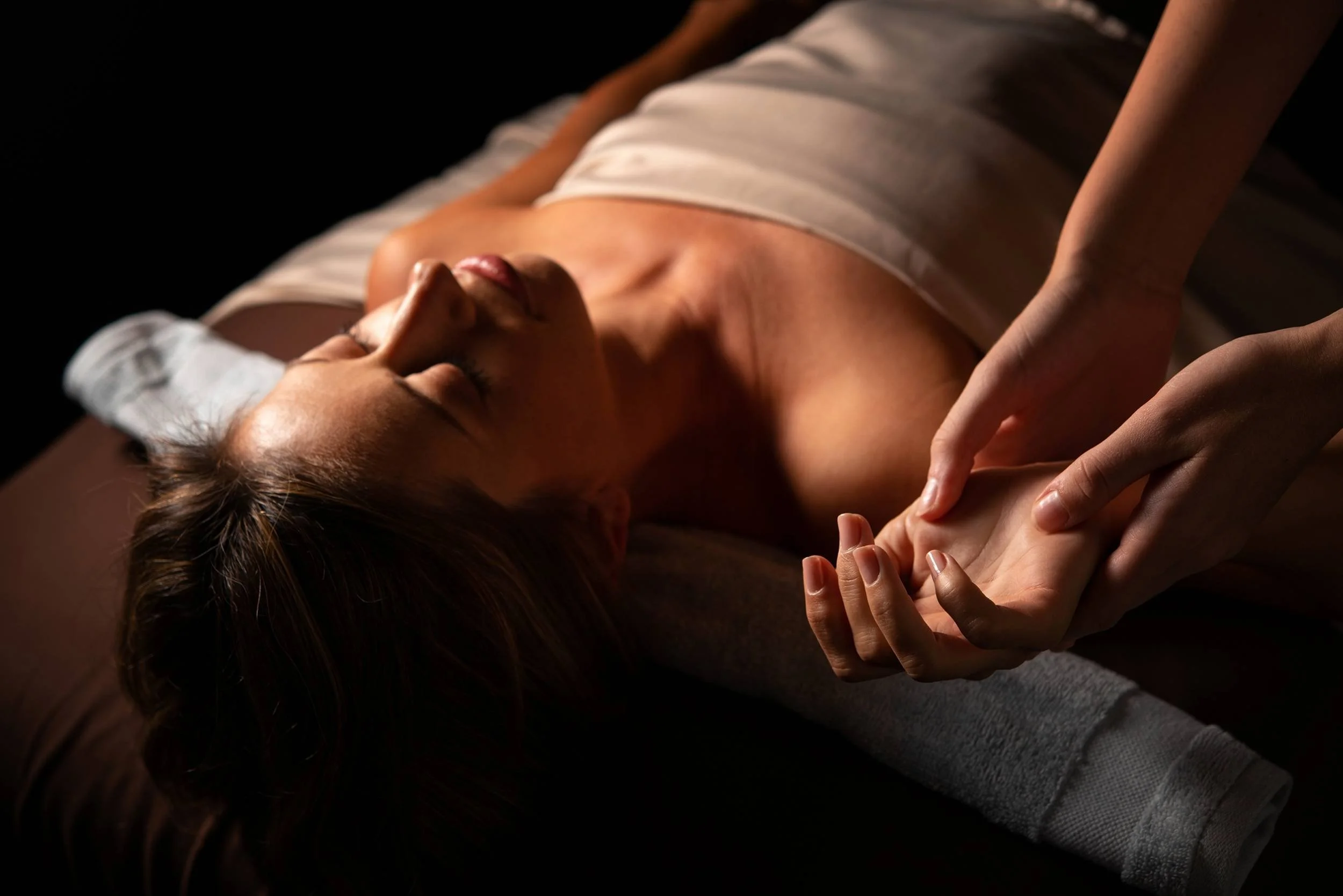 The massage therapist performs reflexology massage on a woman's hand