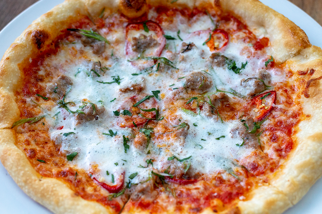  Pizza topped with cheese, sausage, hot peppers, and sprinkled with parsley 