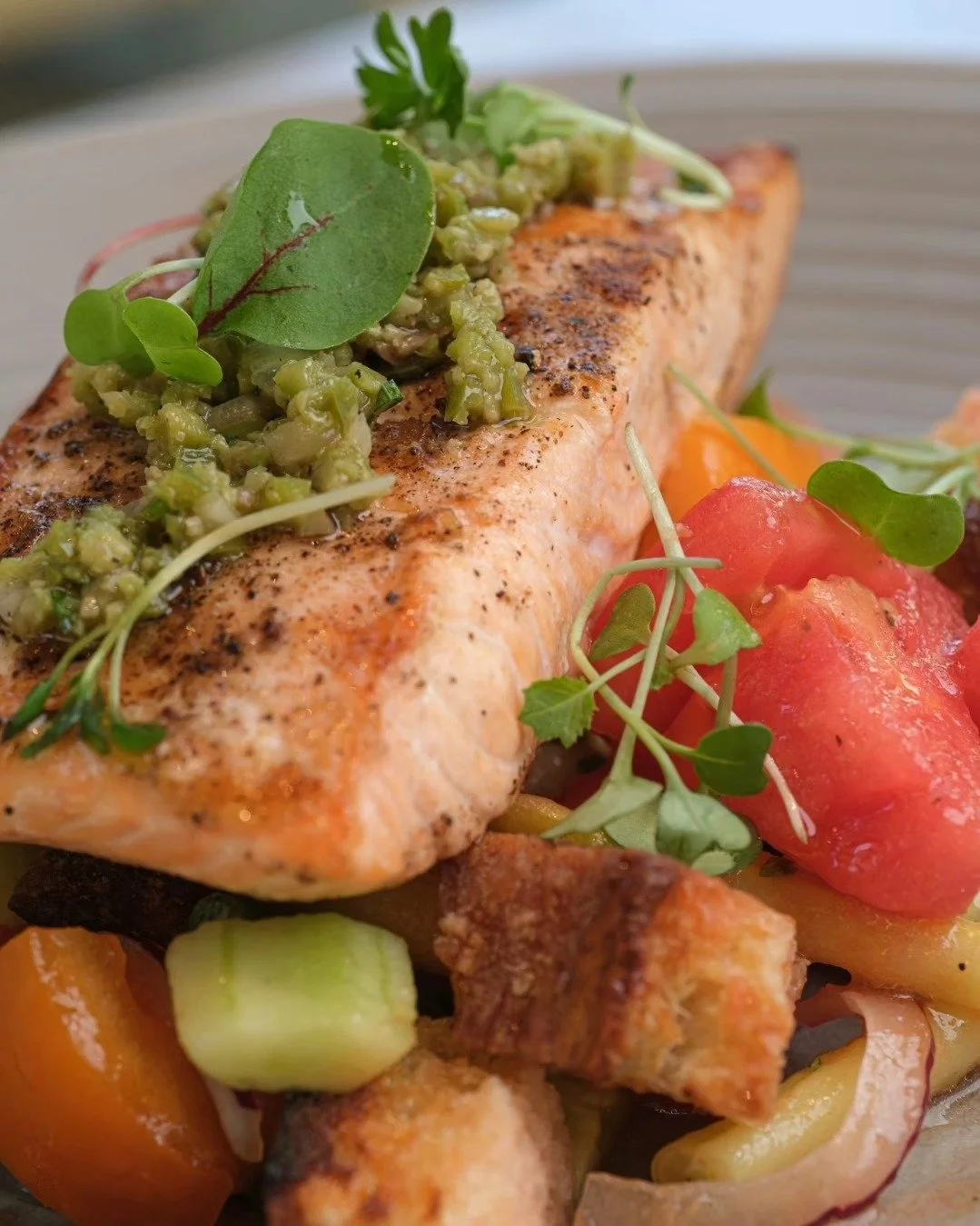 Our Tuscan bread salad of vine ripe tomato, peach, cucumber, torn bread, pickled red onion, garlic, and basil, topped with pistachio pesto and a succulent cut of grilled salmon is so delicious.  Swing by to try it before the end of summer.