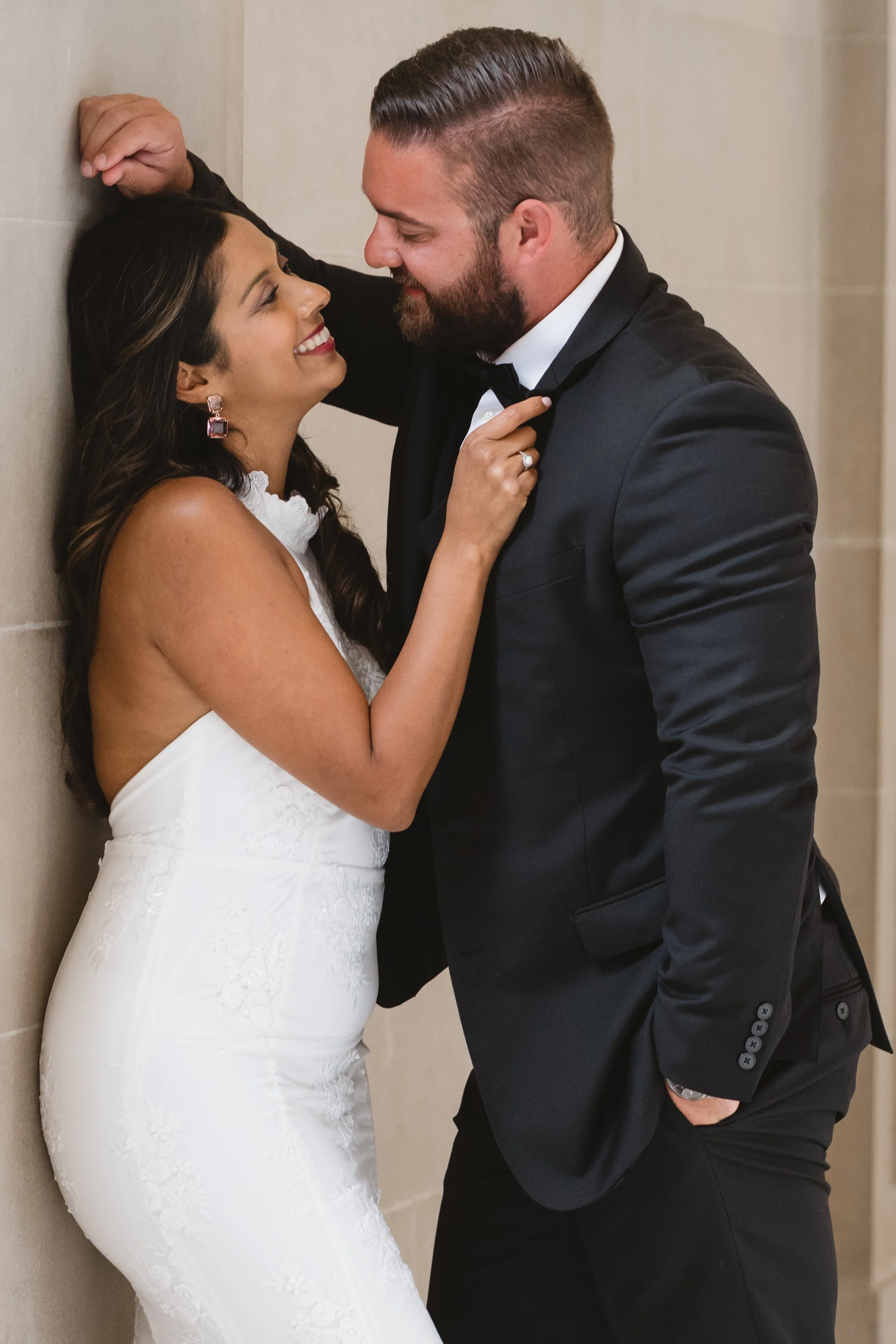 Bride laughing close to her groom's face, her statement earrings catching the light.