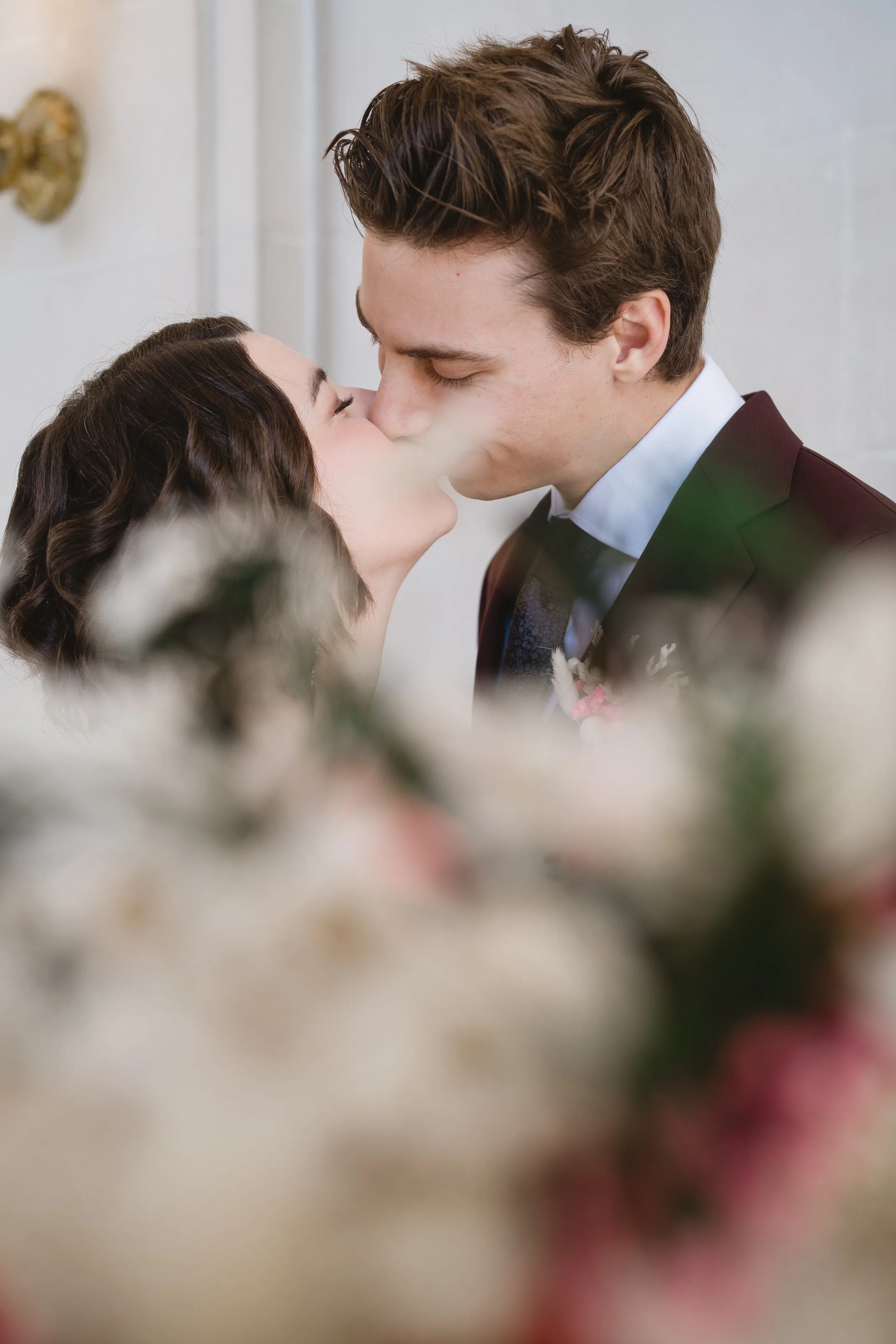 Couple kissing behind a soft-focus bouquet