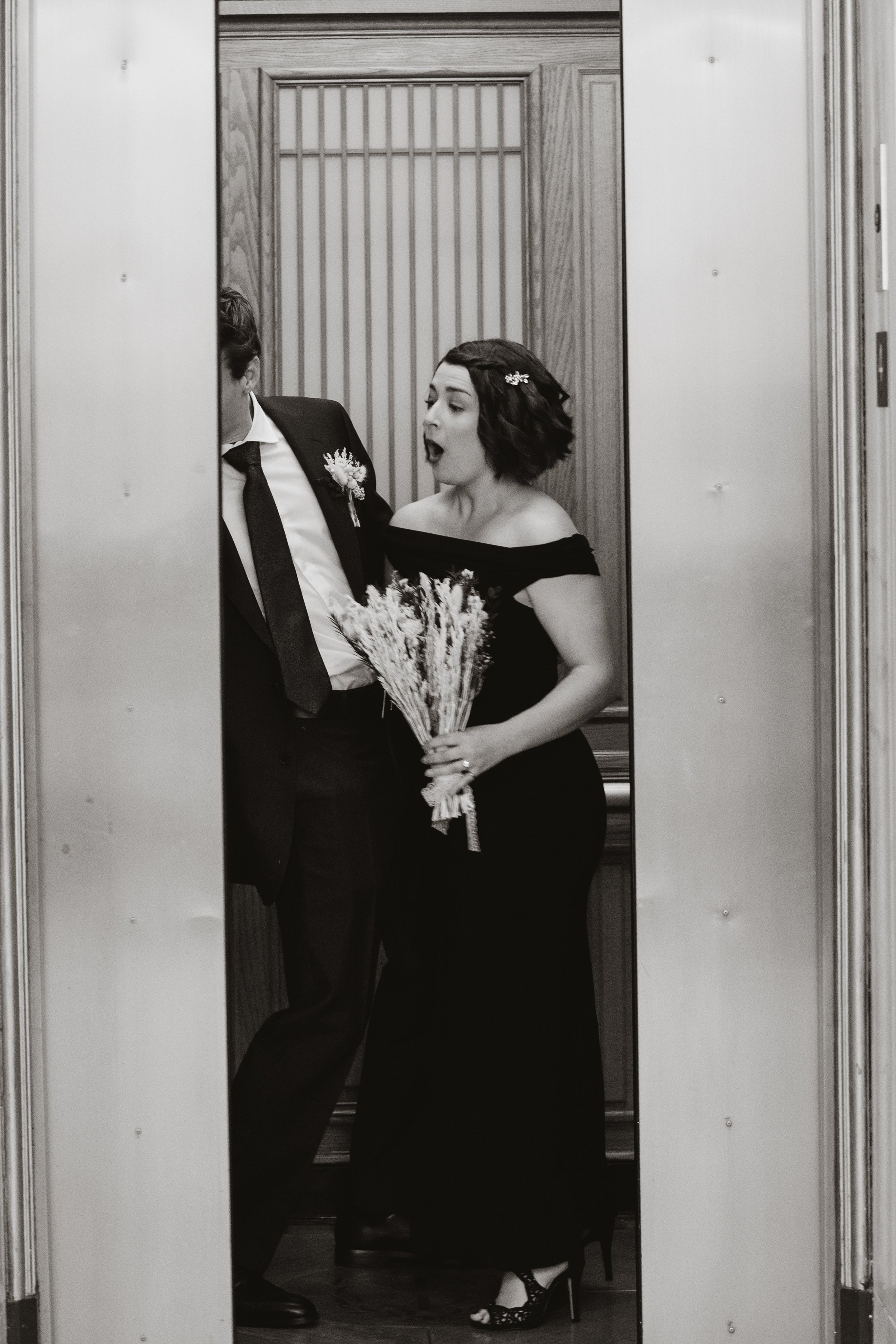 Black and white photo of elevator doors closing on newlyweds