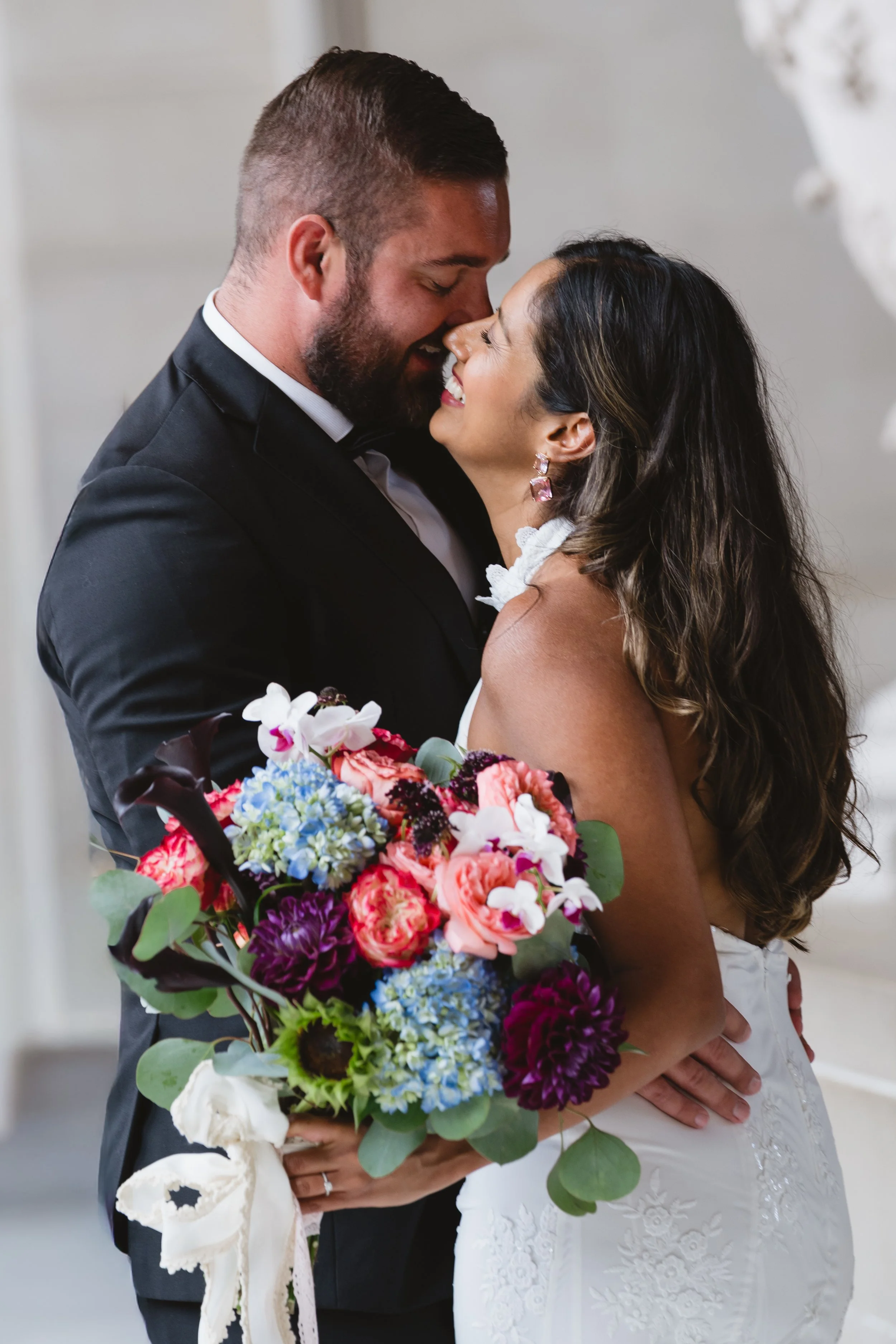 Bride and groom nose to nose, both laughing in a close embrace.