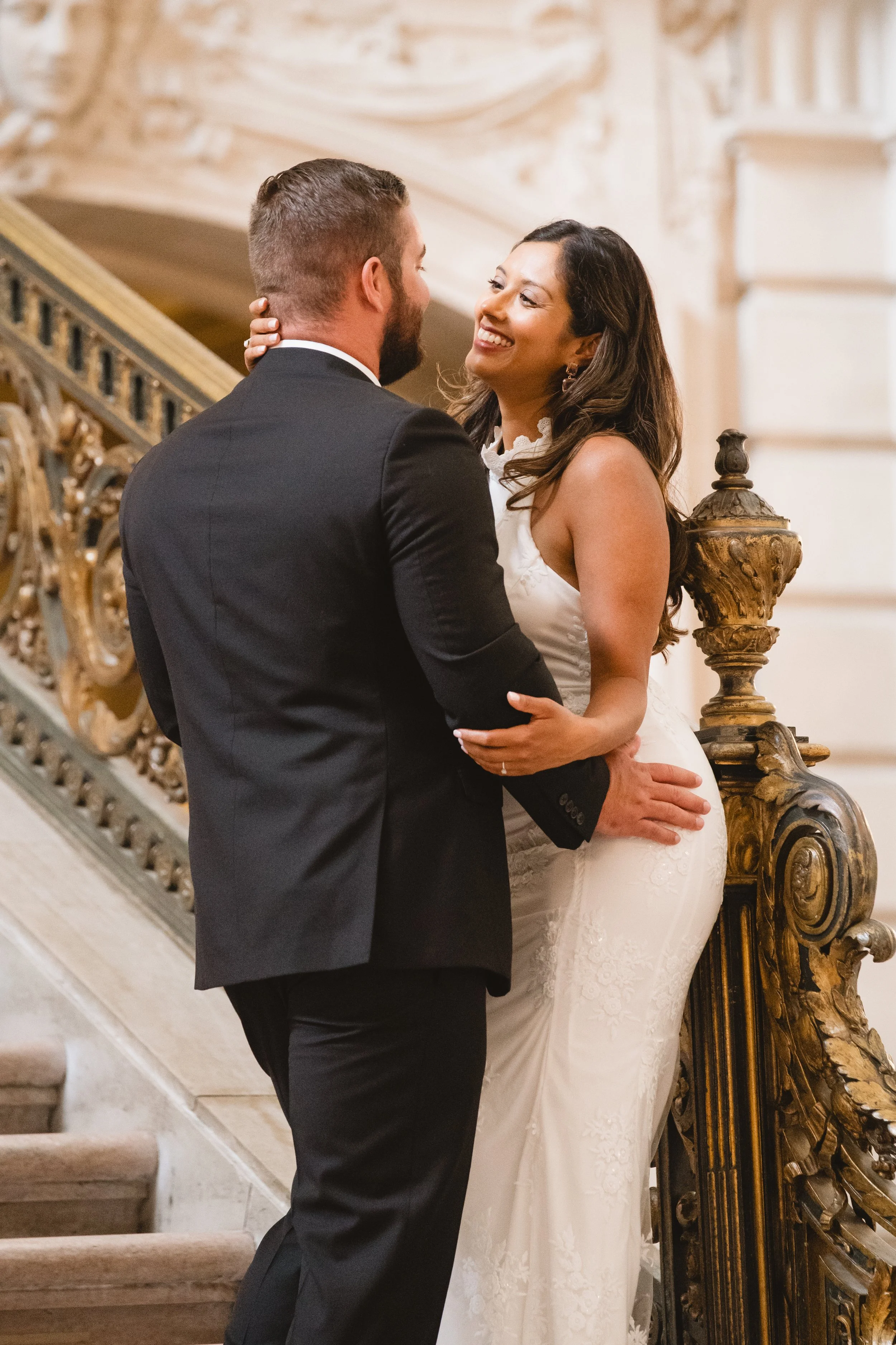 Back view of a couple seated on the staircase, groom's hand resting at his bride's waist.