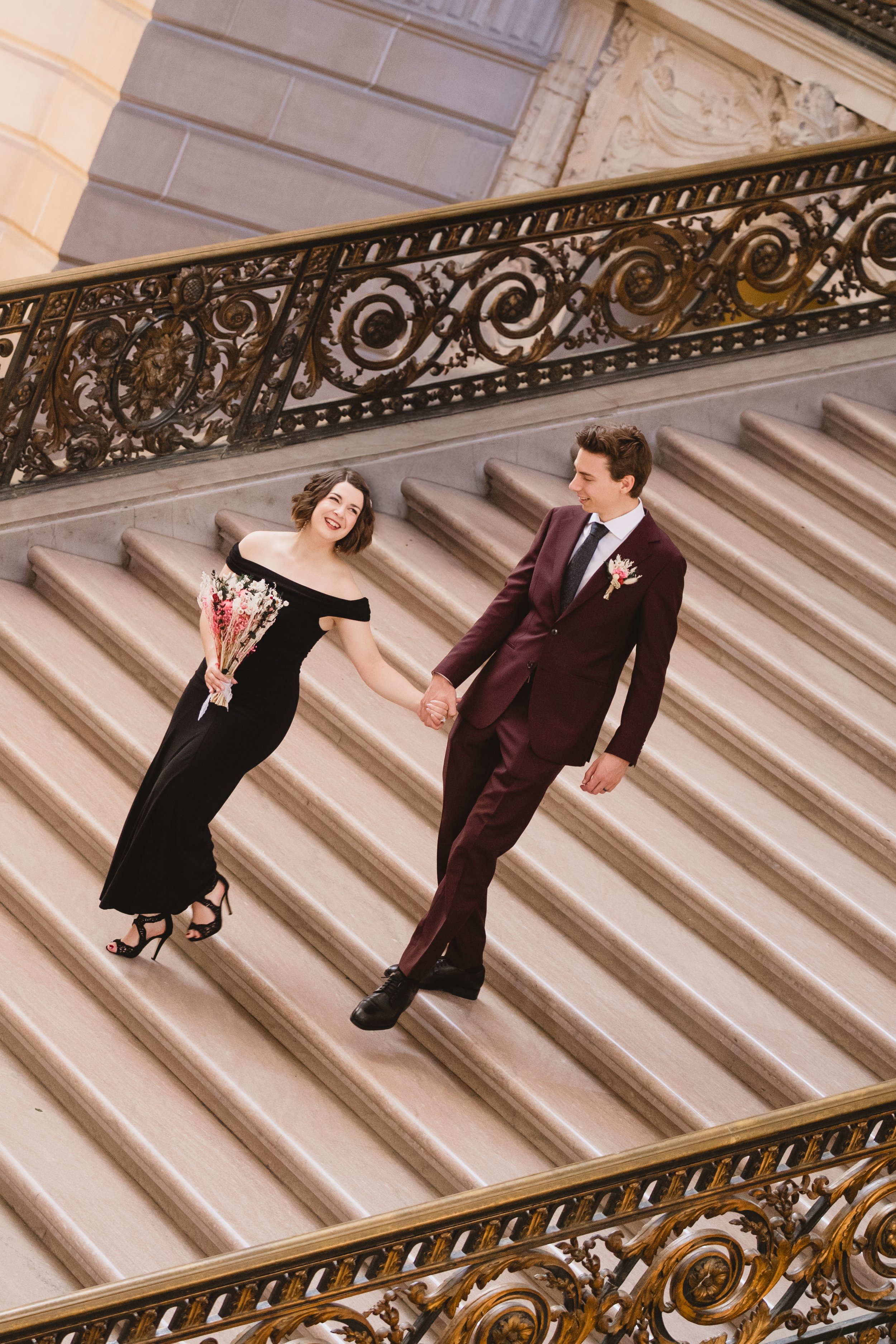 Newlyweds walking down the Grand Staircase at SF City Hall