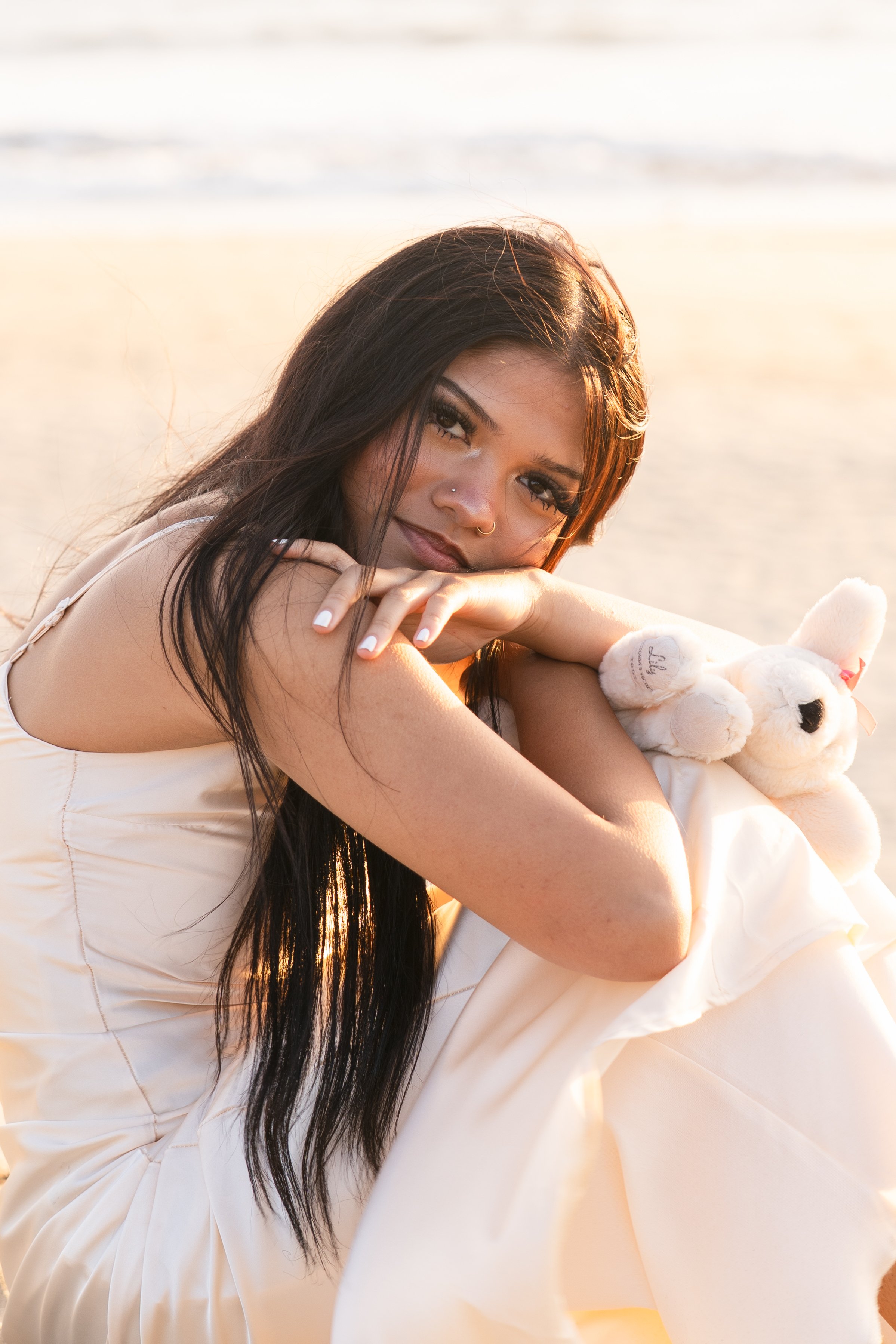 Close-up senior portrait of a girl resting her chin on her arm while holding her childhood stuffed dog