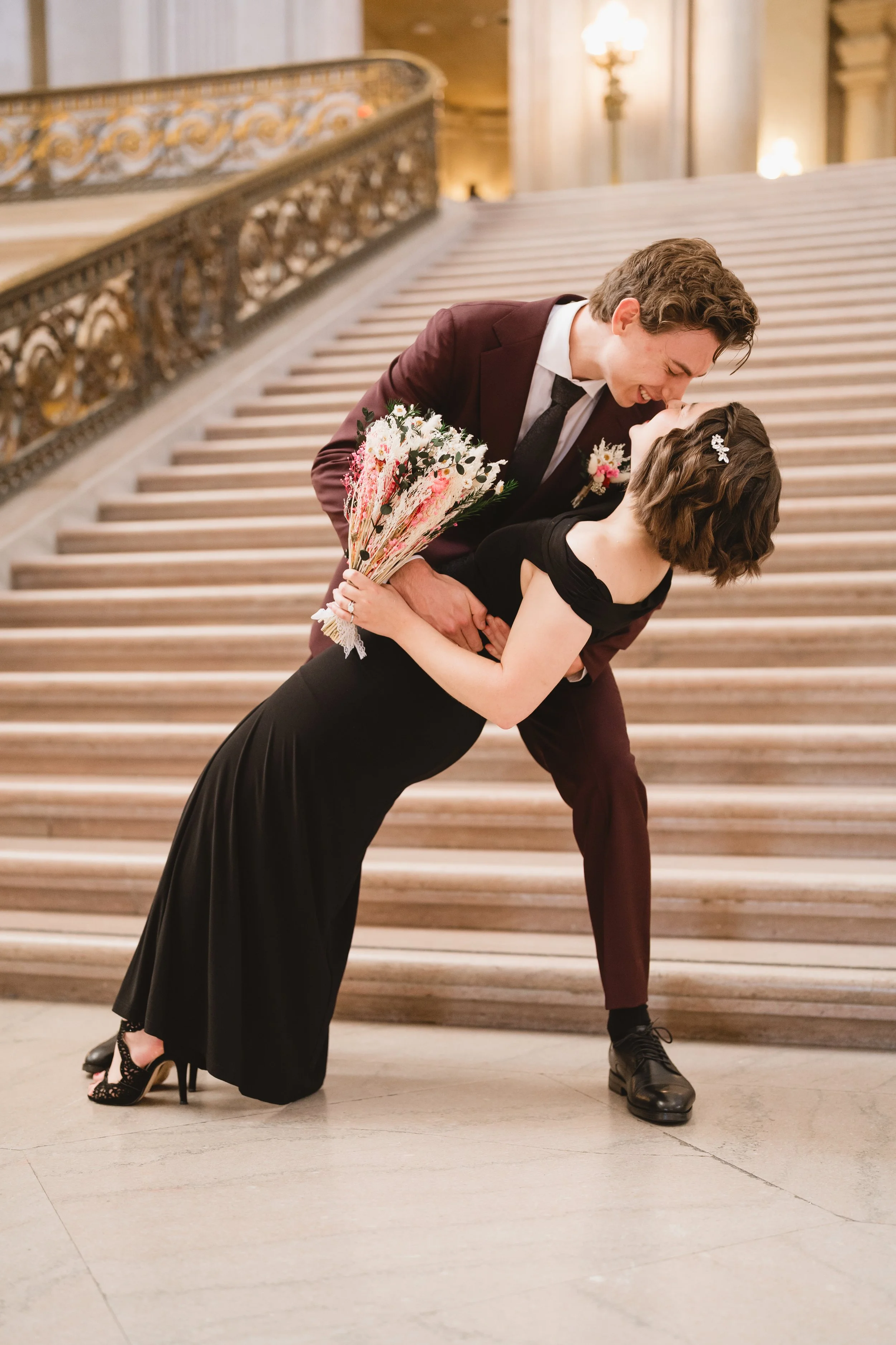 Groom dipping bride for a kiss on the City Hall staircase