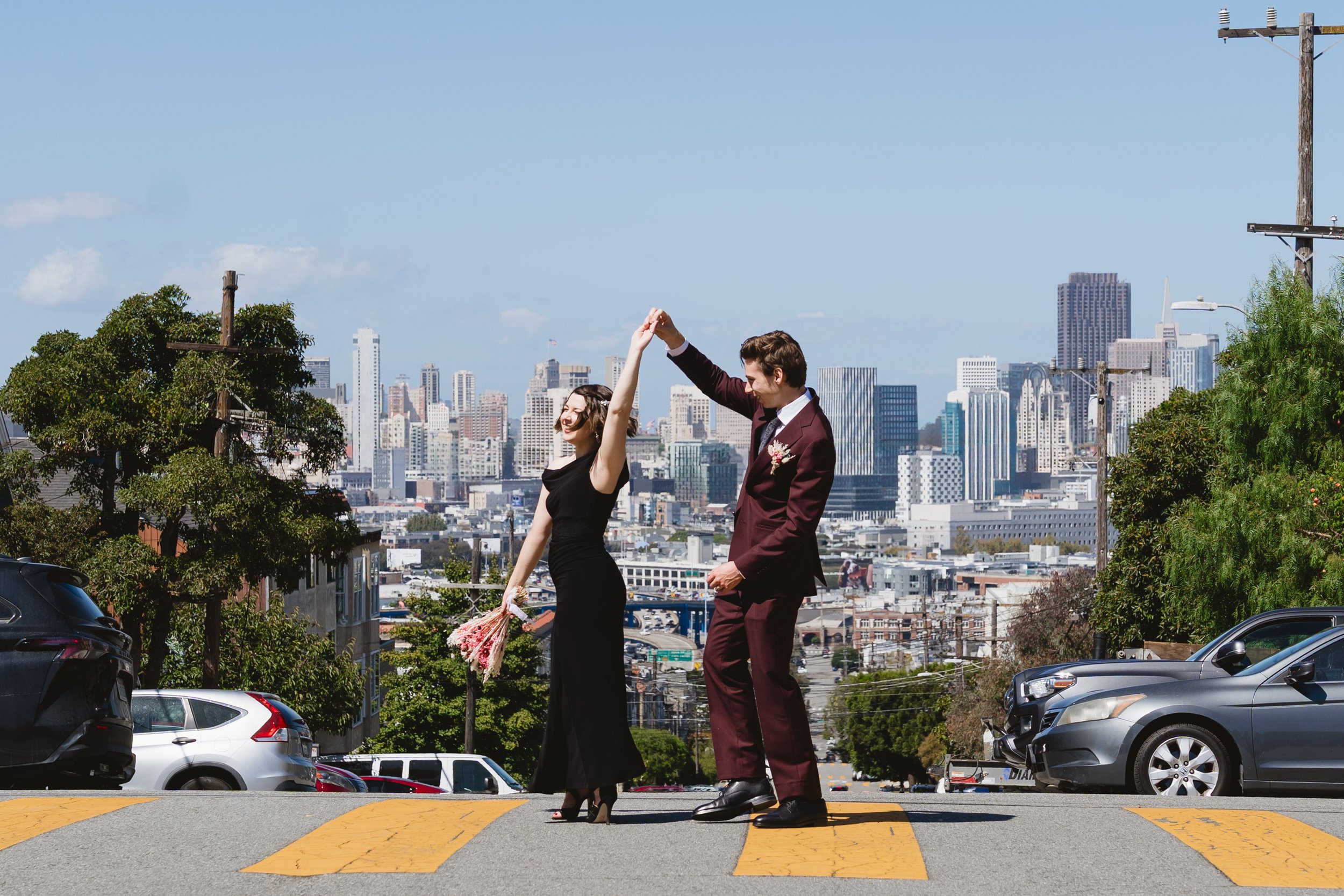 Newlyweds twirling in a Potrero Hill crosswalk with a skyline view